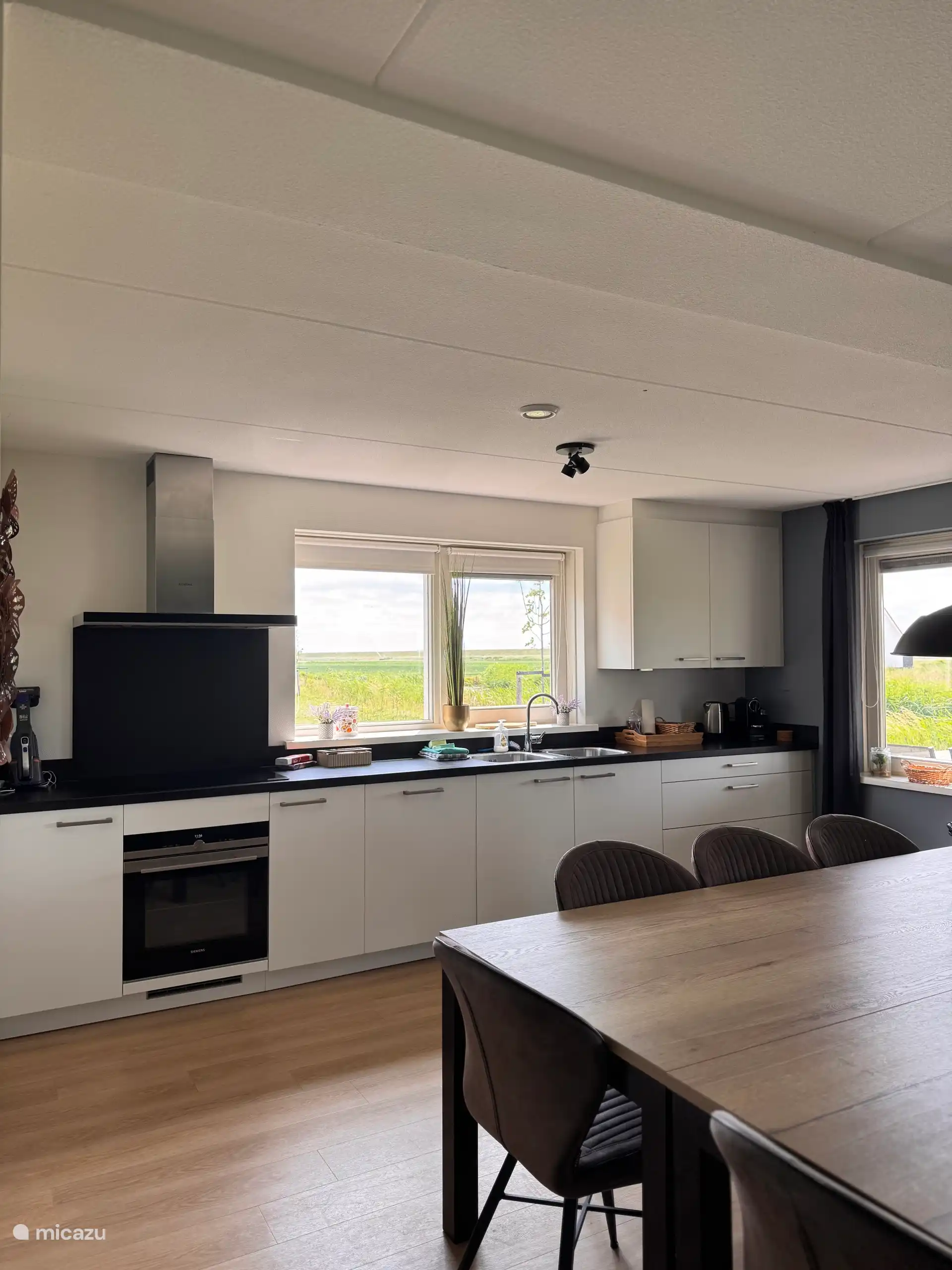 De lichte keuken met strakke lijnen en grote ramen zorgt voor een prachtige lichtinval. Terwijl je kookt geniet je van het weidse uitzicht en de rustige, open sfeer.