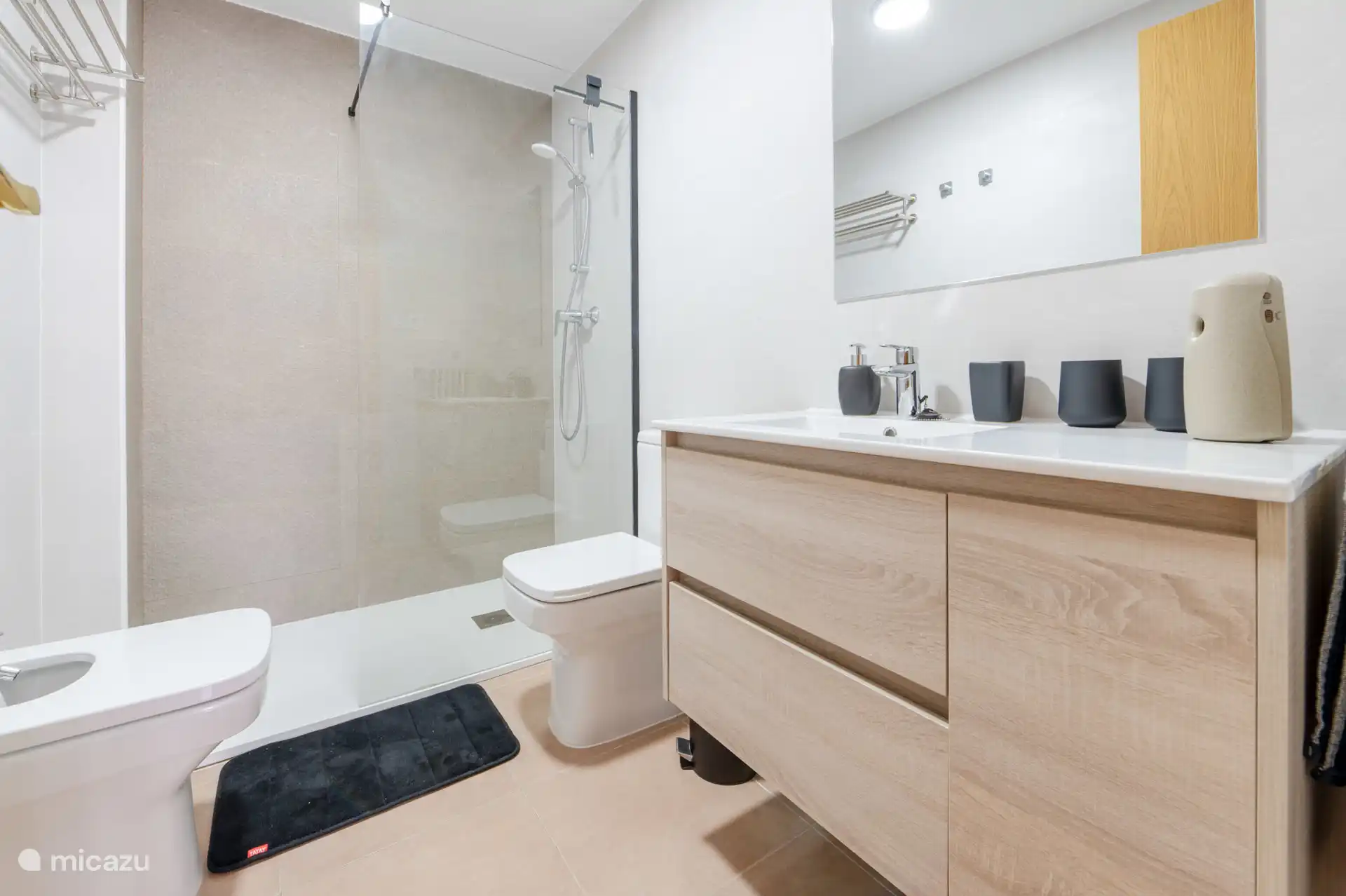 Badezimmer mit begehbarer Dusche, Bidet, WC und Waschbecken.