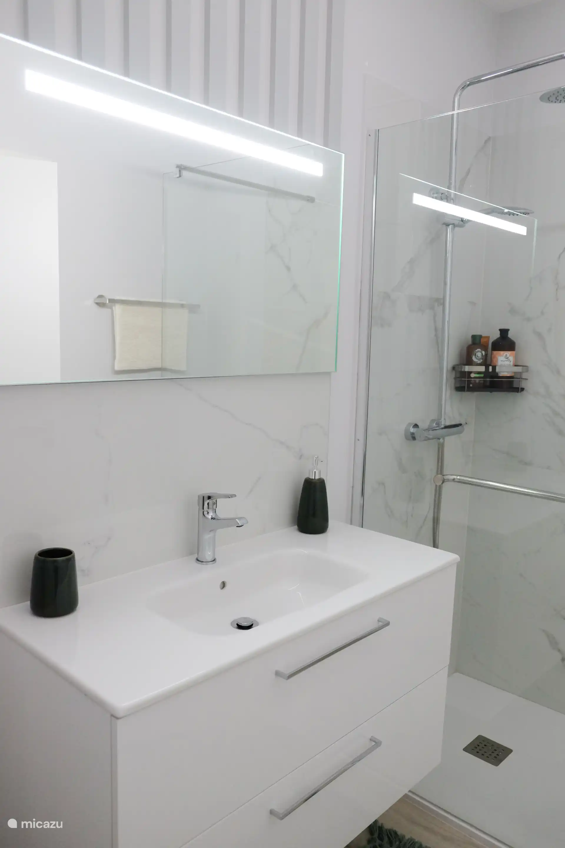 Für Schlafzimmer zwei und drei gibt es ein Gemeinschaftsbad mit luxuriöser Regendusche, WC, Bidet, Waschbecken und beheiztem Spiegel.