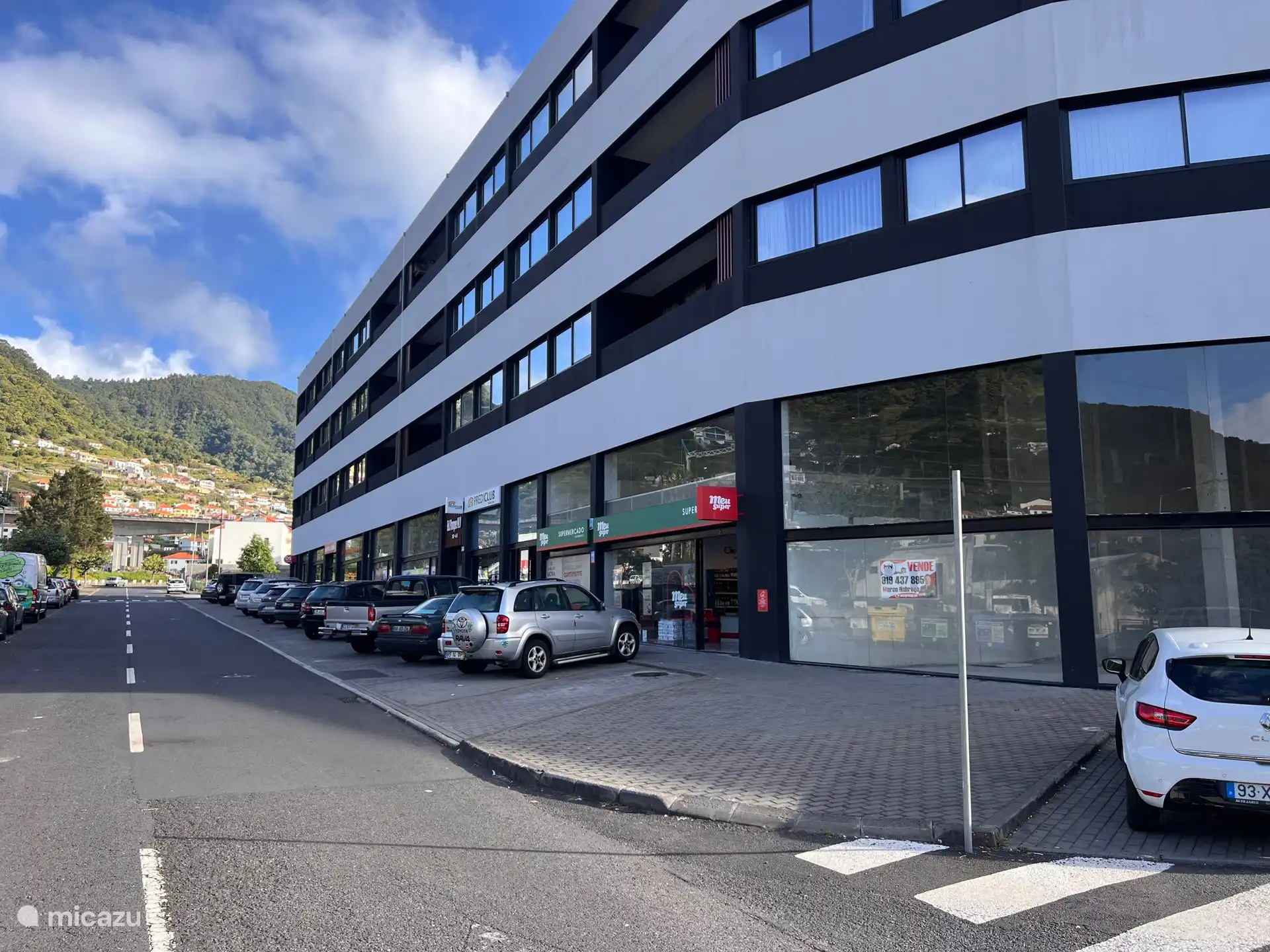 Außenansicht des Apartmentkomplexes mit Supermarkt und ausreichend kostenlosen Parkplätzen darunter.