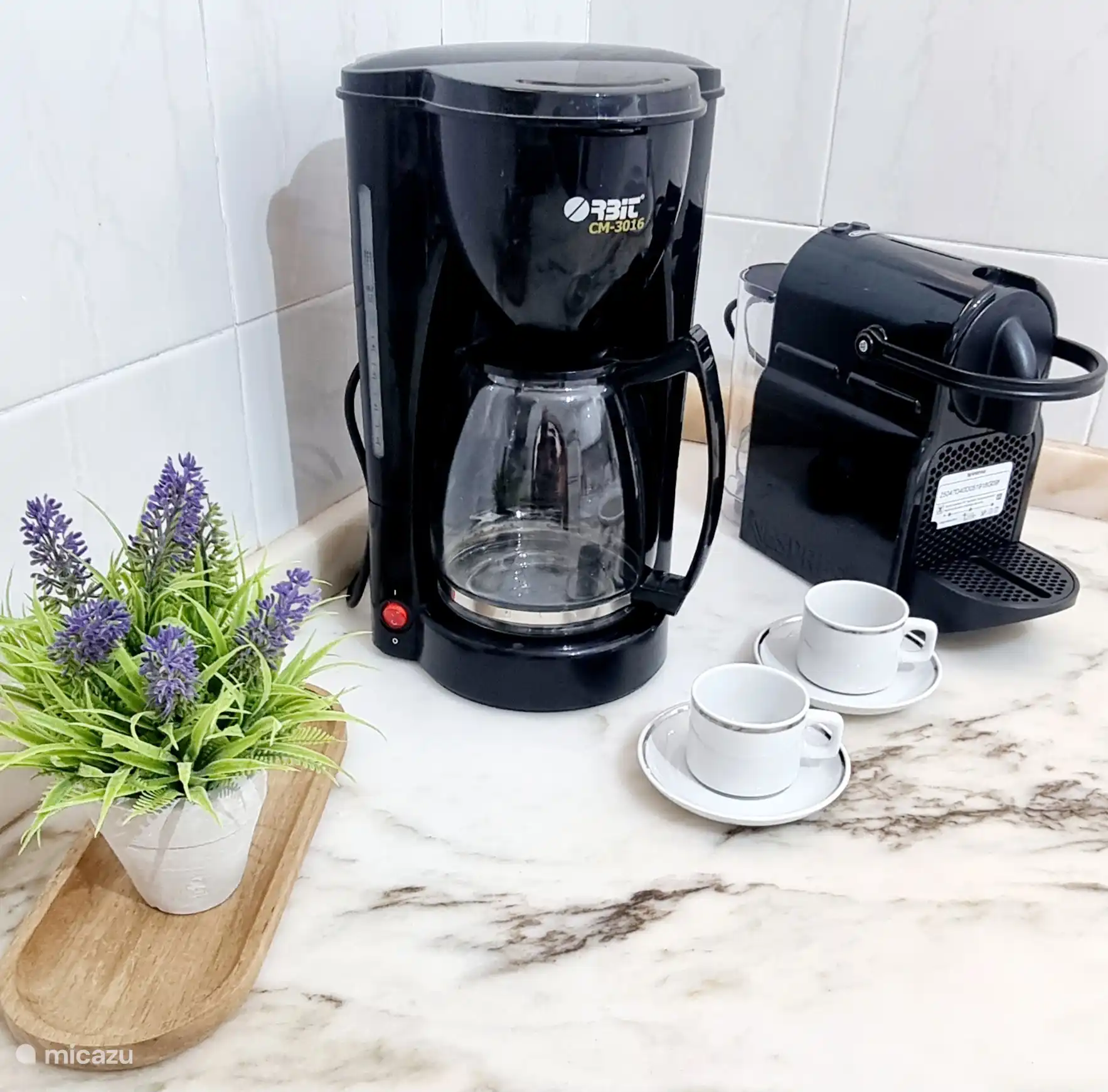 Eine voll ausgestattete Küche mit einem Kühlschrank, einem Herd, einem Backofen sowie Tee- und Kaffeezubehör.