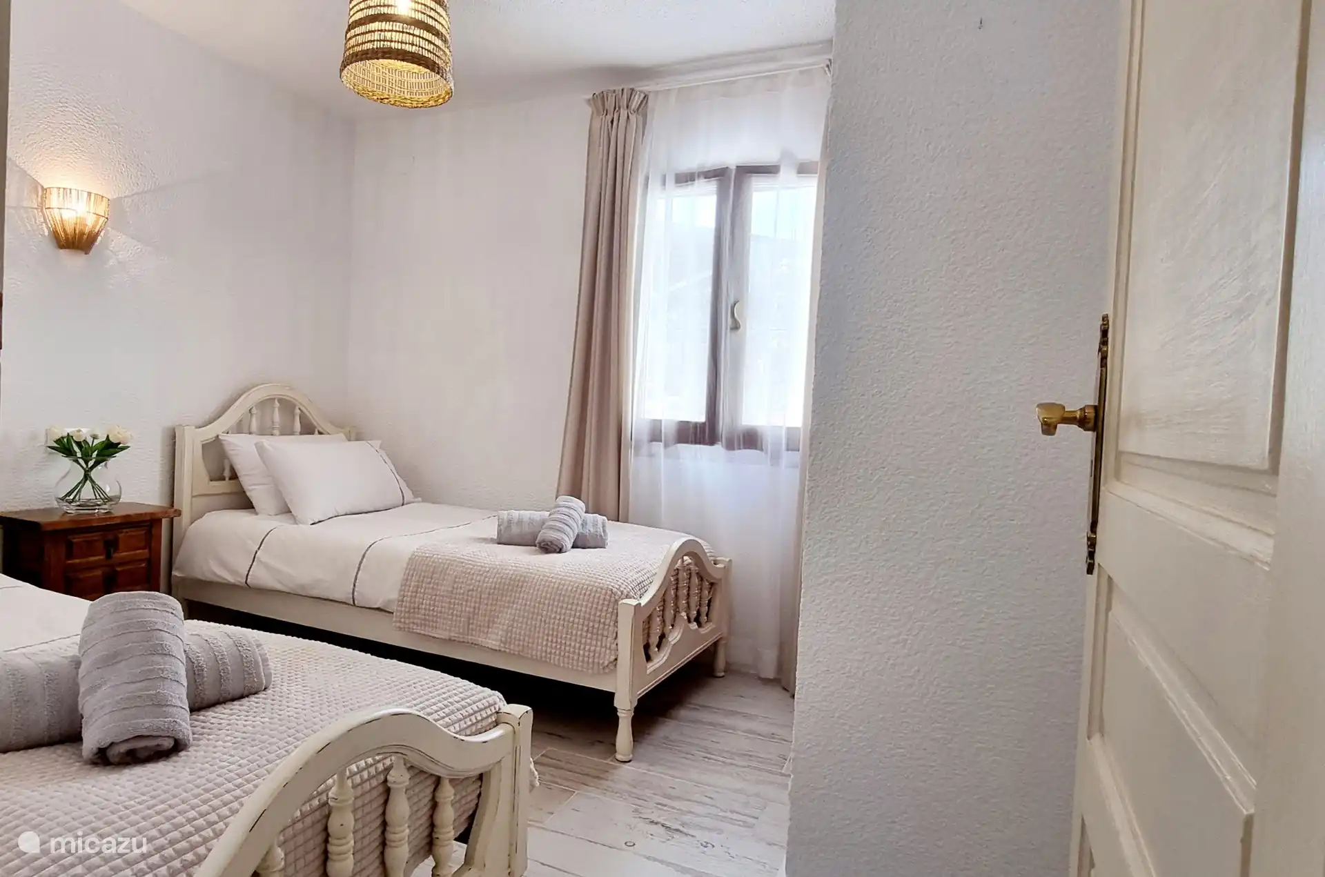 Das zweite Schlafzimmer verfügt über zwei Einzelbetten, die in ein luxuriöses Kingsize-Bett umgewandelt werden können. Gegenüber befindet sich das zweite Badezimmer, das elegant mit einer ebenerdigen Dusche ausgestattet ist.