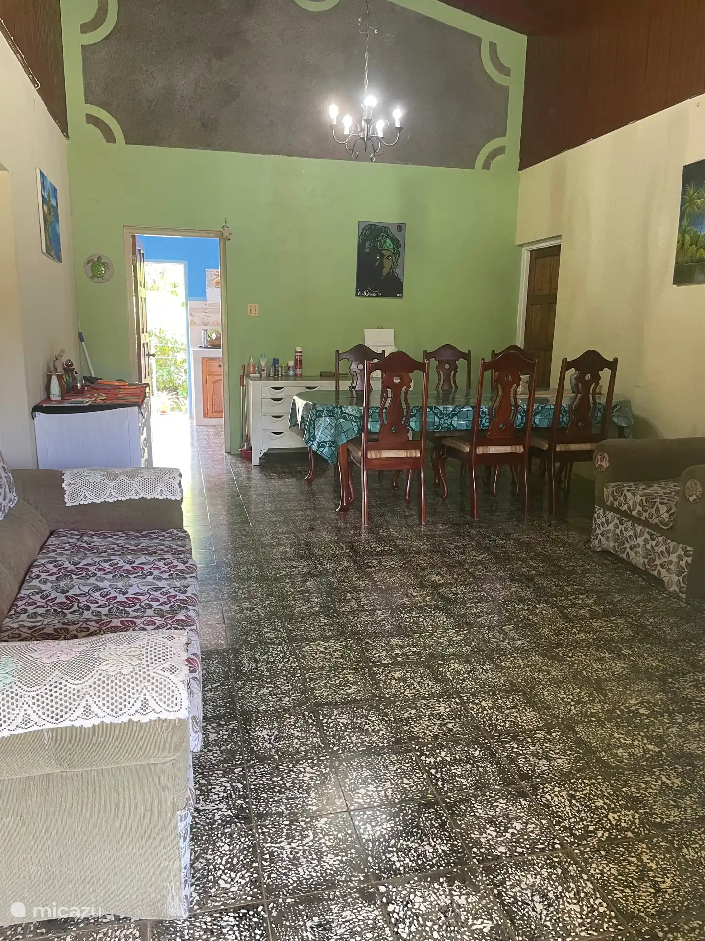 Das Wohnzimmer mit großem Esstisch mit sechs Stühlen, Sofa, zwei Sitzgelegenheiten und TV 