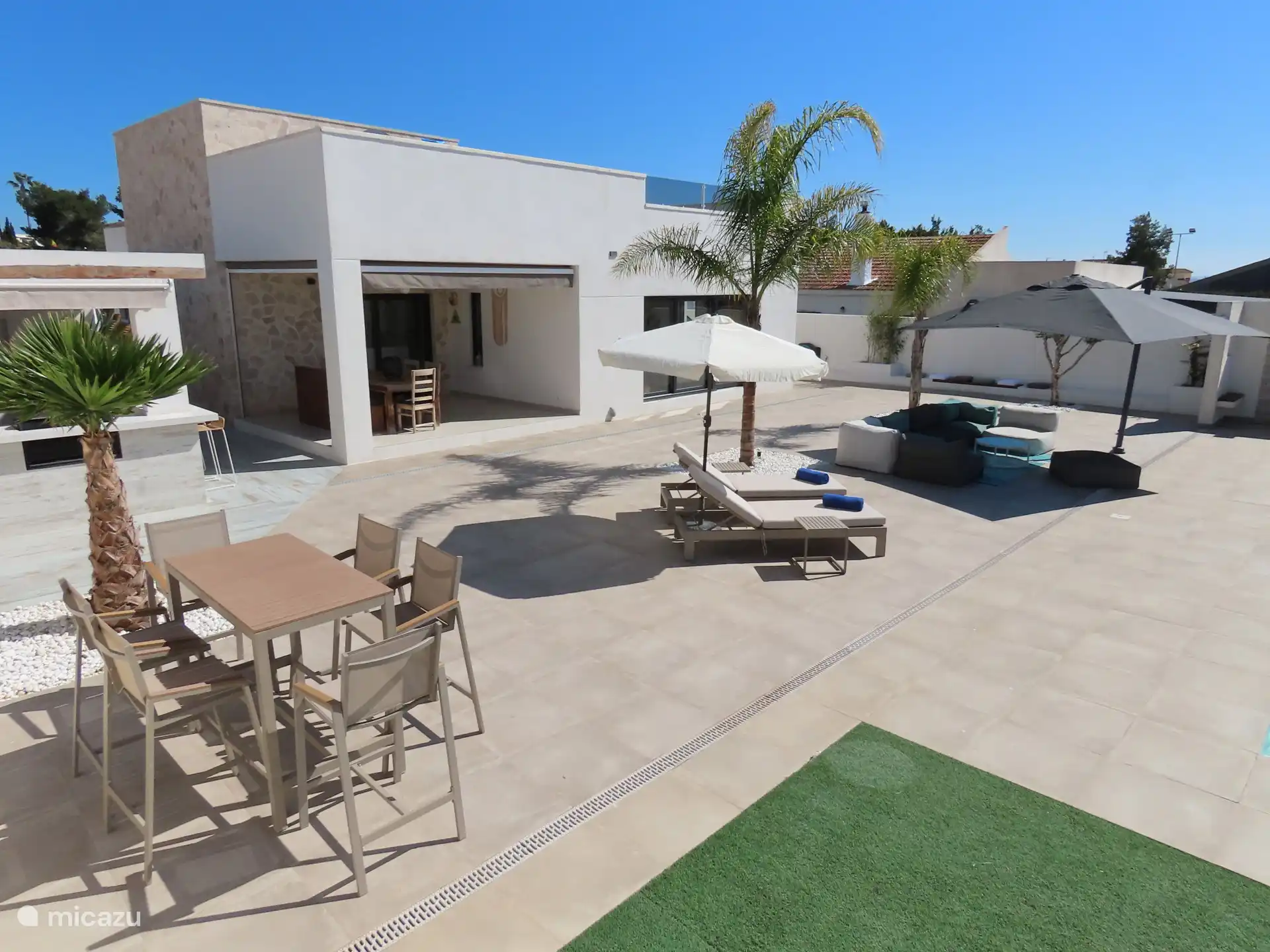 Bequeme Sonnenliegen, Stehtisch, luxuriöser Lounge-Sitz und überdachte Veranda mit Essbereich.