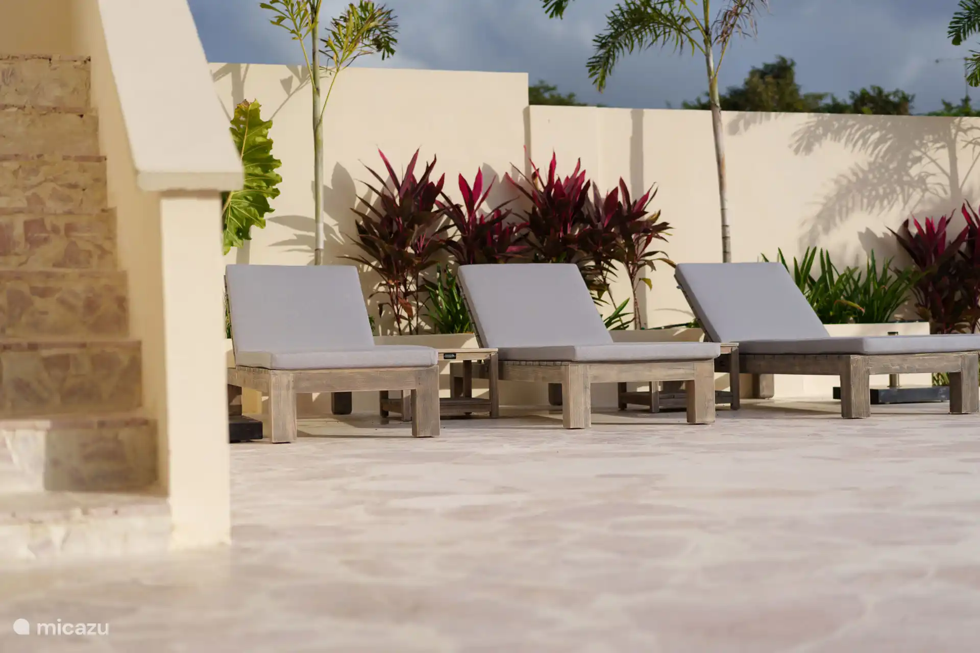 Sonnenliegen und Sonnenschirme auf der großzügigen Terrasse rund um den Pool