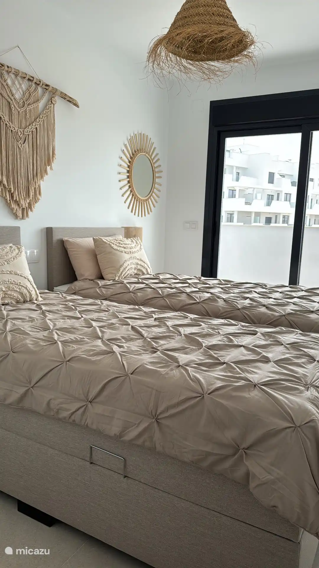 Dormitorio de invitados con persiana eléctrica y acceso a terraza. Hay un montón de perchas en los armarios.