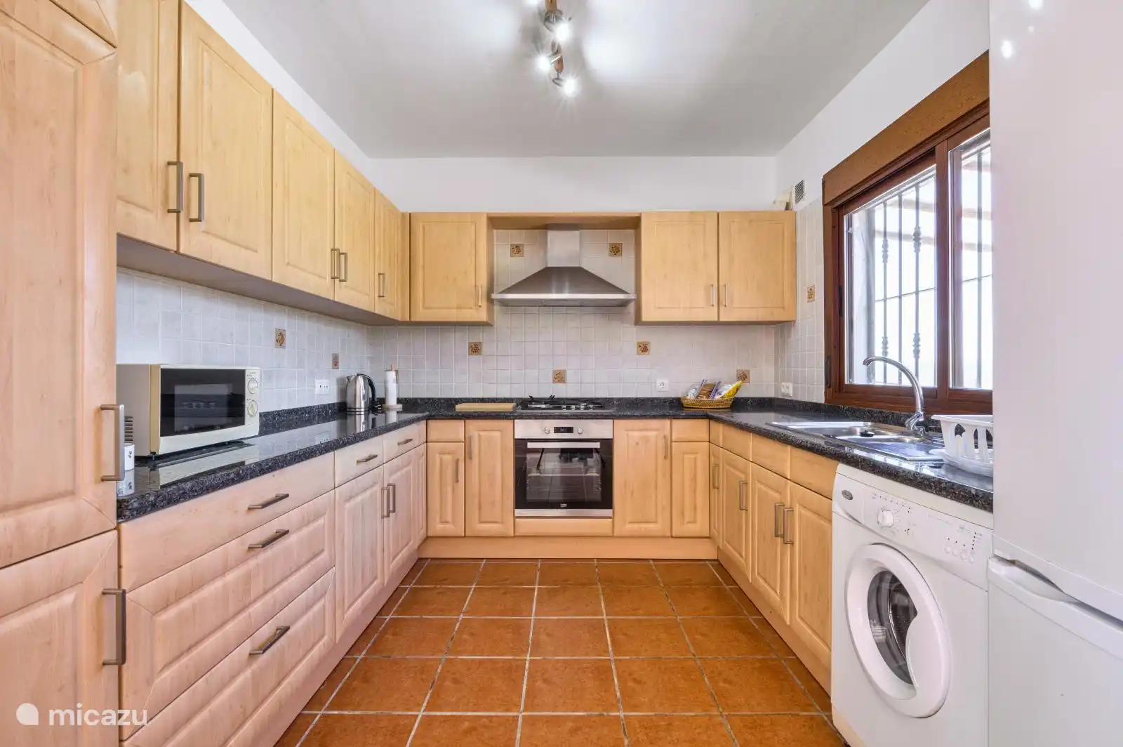 Kitchen with washing machine, stove & oven, microwave, fridge, kettle, etc