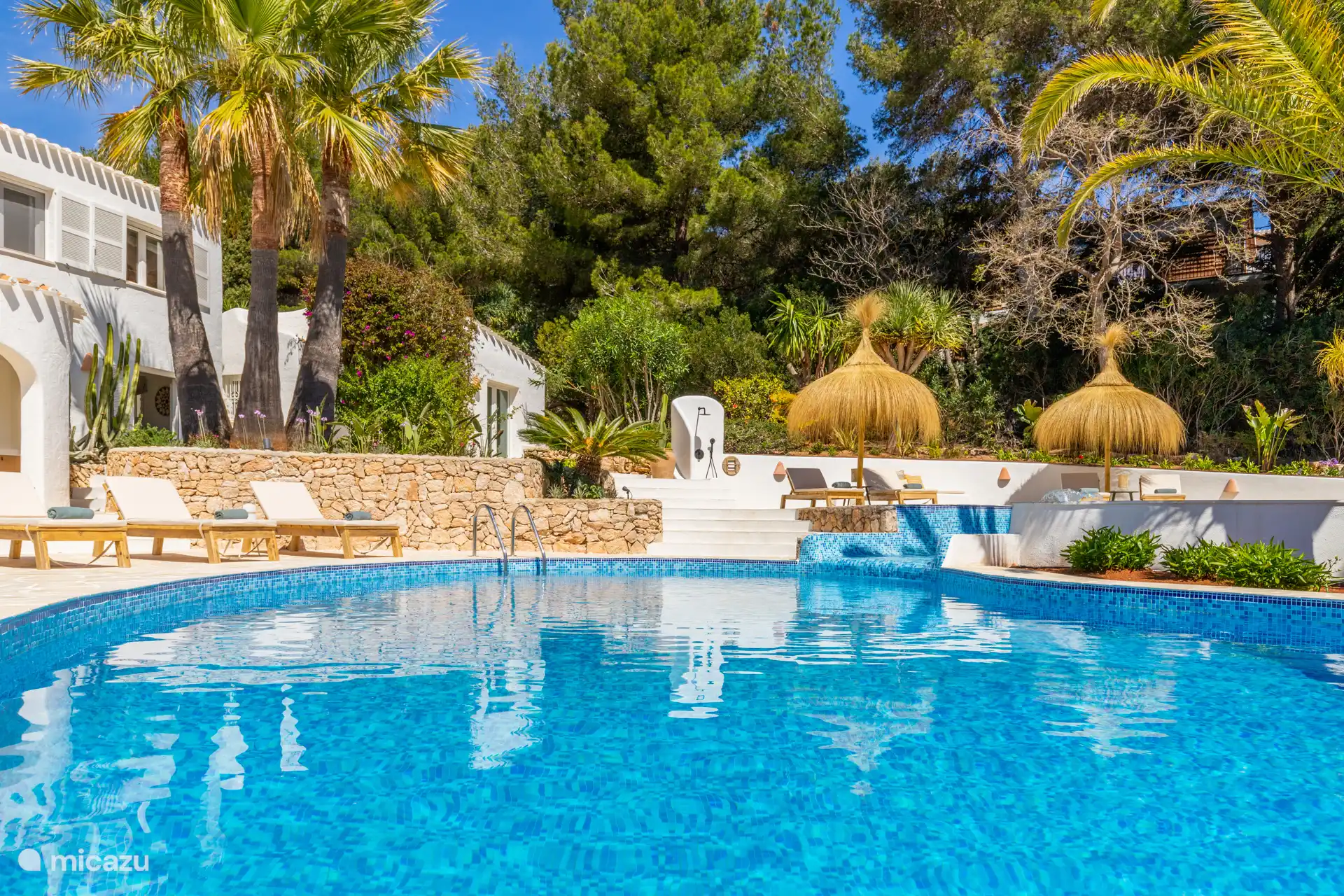 Swimmingpool mit luxuriösen Sonnenliegen, Sonnenschirmen und Außendusche