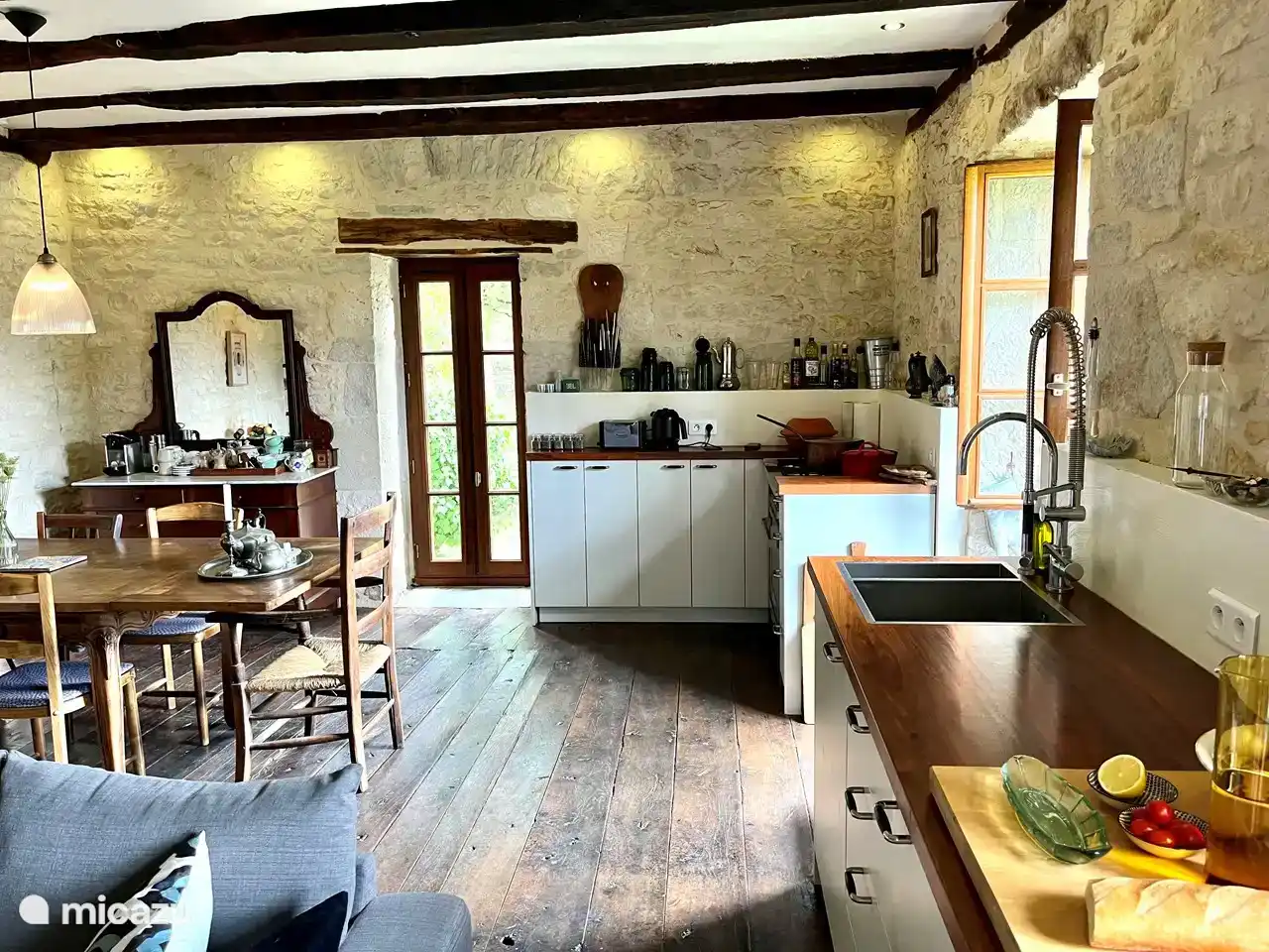 The kitchen/living room, with a Nespresso coffee machine and milk frother on the left side of the cupboard with mirror. On the right the stove with oven, kettle and toaster.