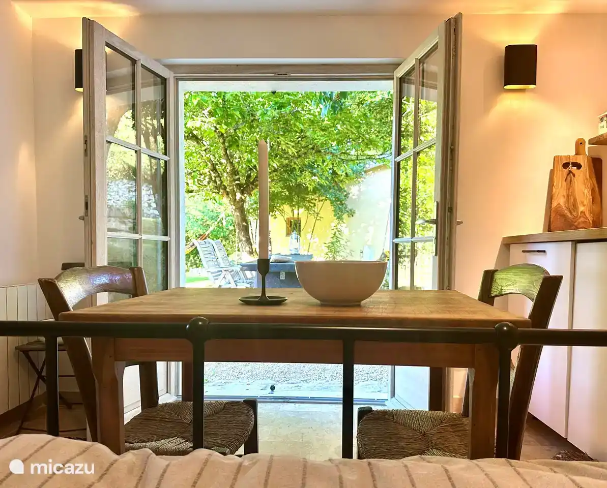 View from the bed in the studio. With the table, the kitchen corner and outside a large table with bench and chairs.