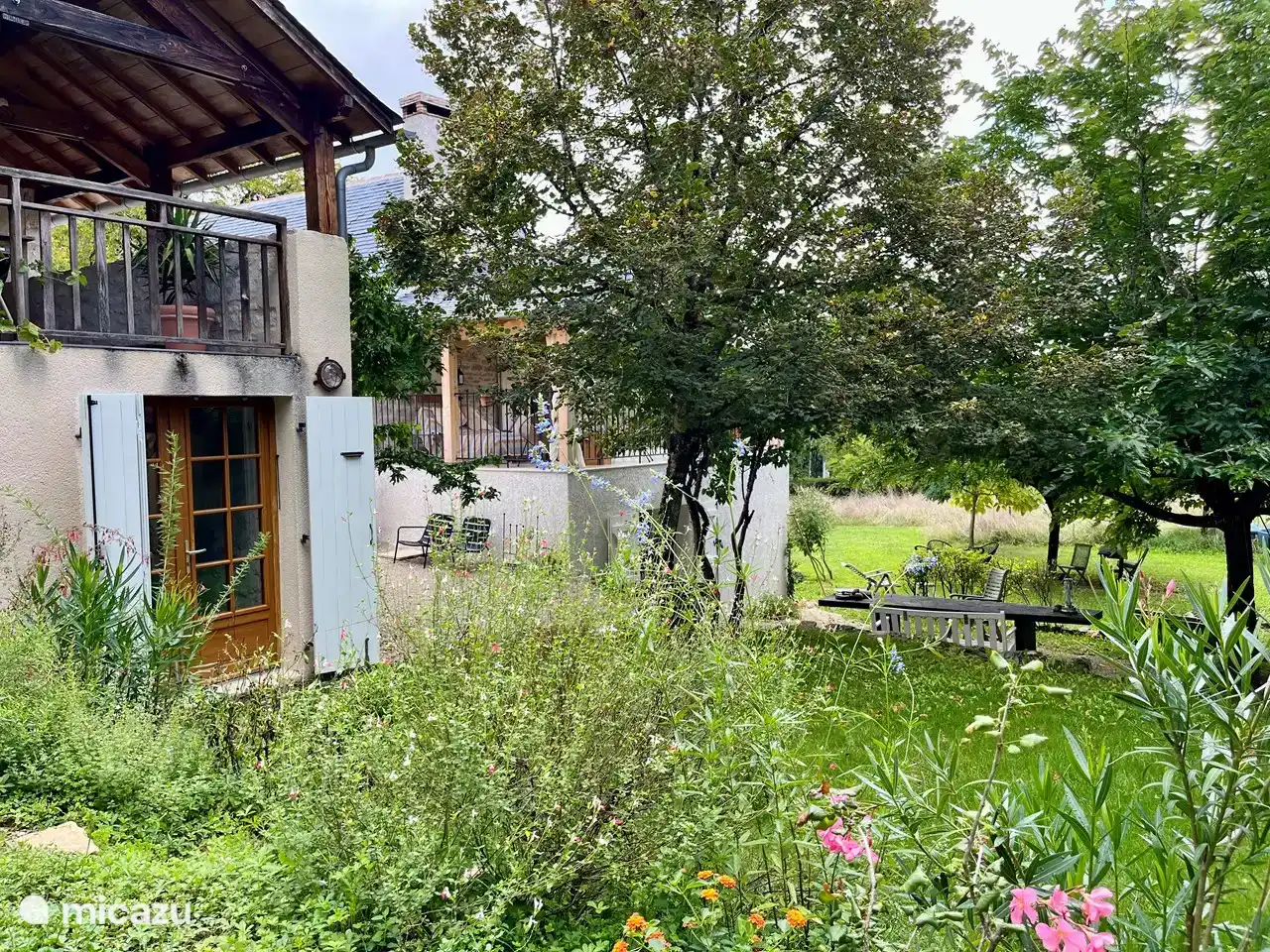 To the left the two covered terraces, the first with double bed and the rear with dining table, sitting area and sunbed. To the right under the trees a large outdoor table.