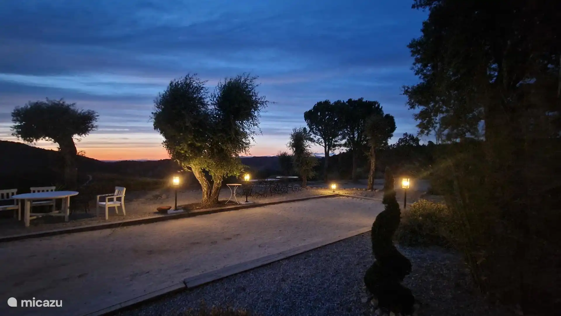 Bowlingbahn am Abend mit Sitzgelegenheiten, Gartenbeleuchtung und untergehender Sonne