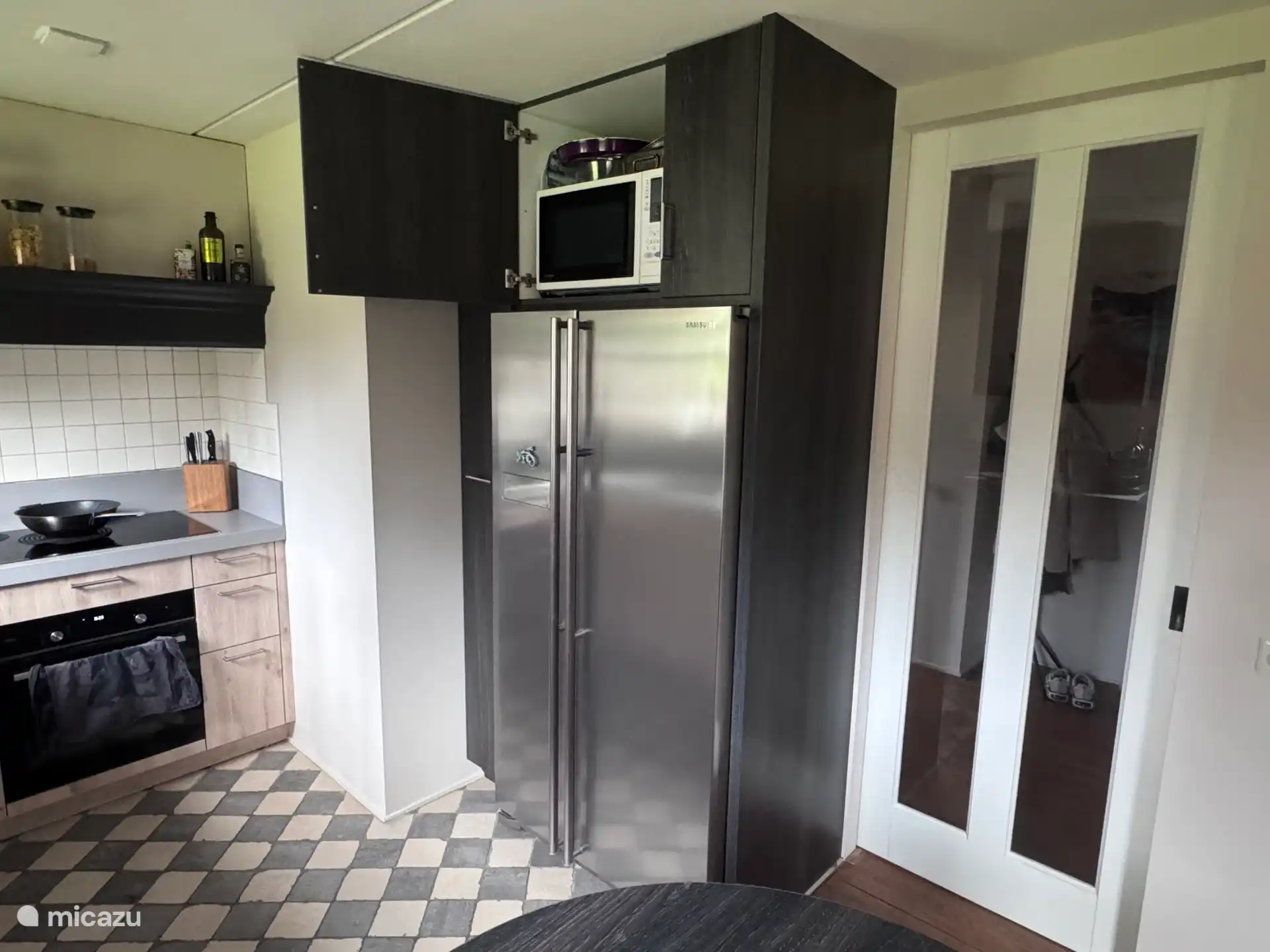 Keuken met inductieplaat (5 zones), hete lucht/stoom oven, ruime koel- en vrieskast, magnetron en schuifdeur naar hal.