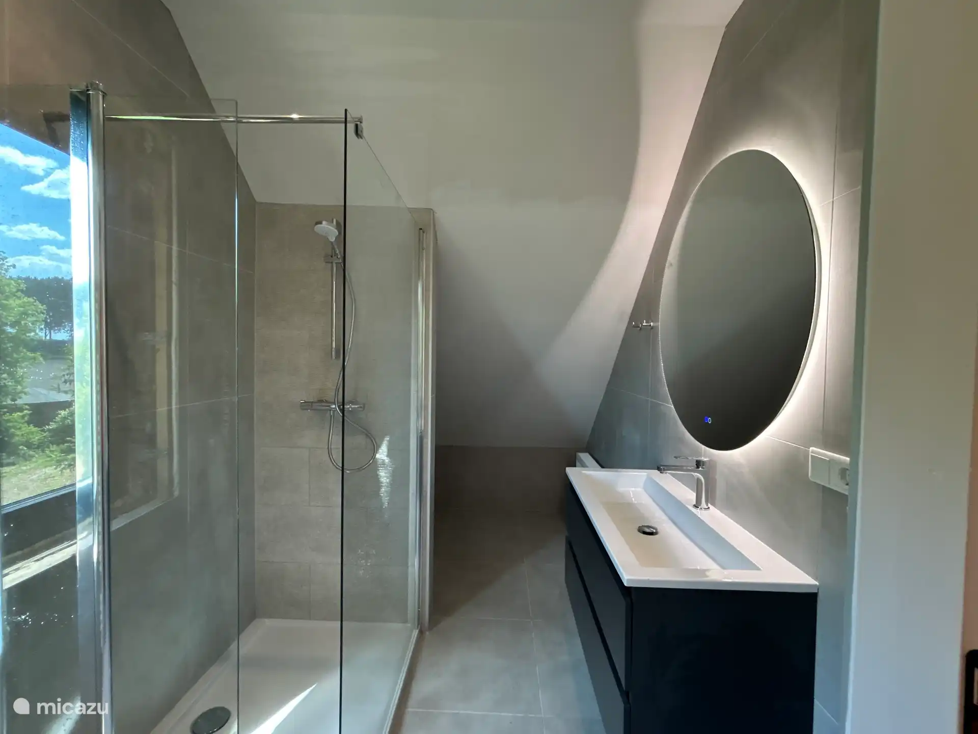 Bathroom with walk-in shower and large round mirror