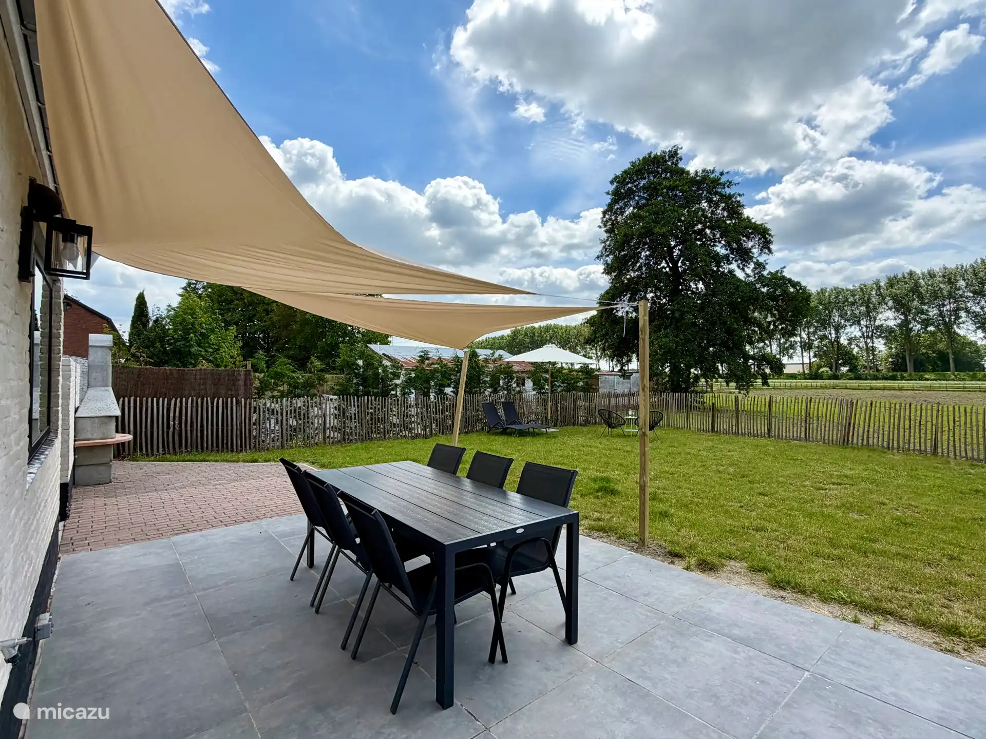 Terraza soleada con vistas al pólder. Conjunto de jardín con 6 sillas. En la esquina del jardín hay una zona de descanso con tumbonas y asientos tipo cubo. BBQ