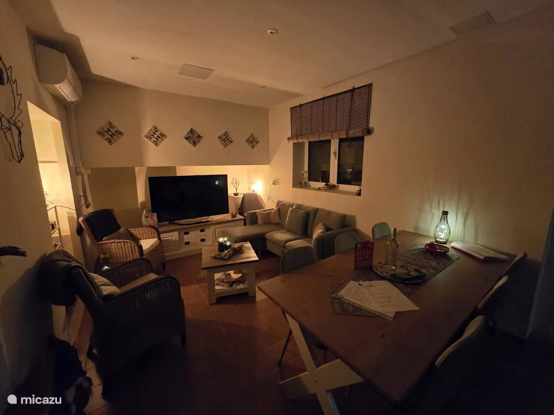 Wohn-/Esszimmer mit Esstisch und 6 Stühlen, 2 Stühlen und kleinem Sofa. Tisch und Fernseher 