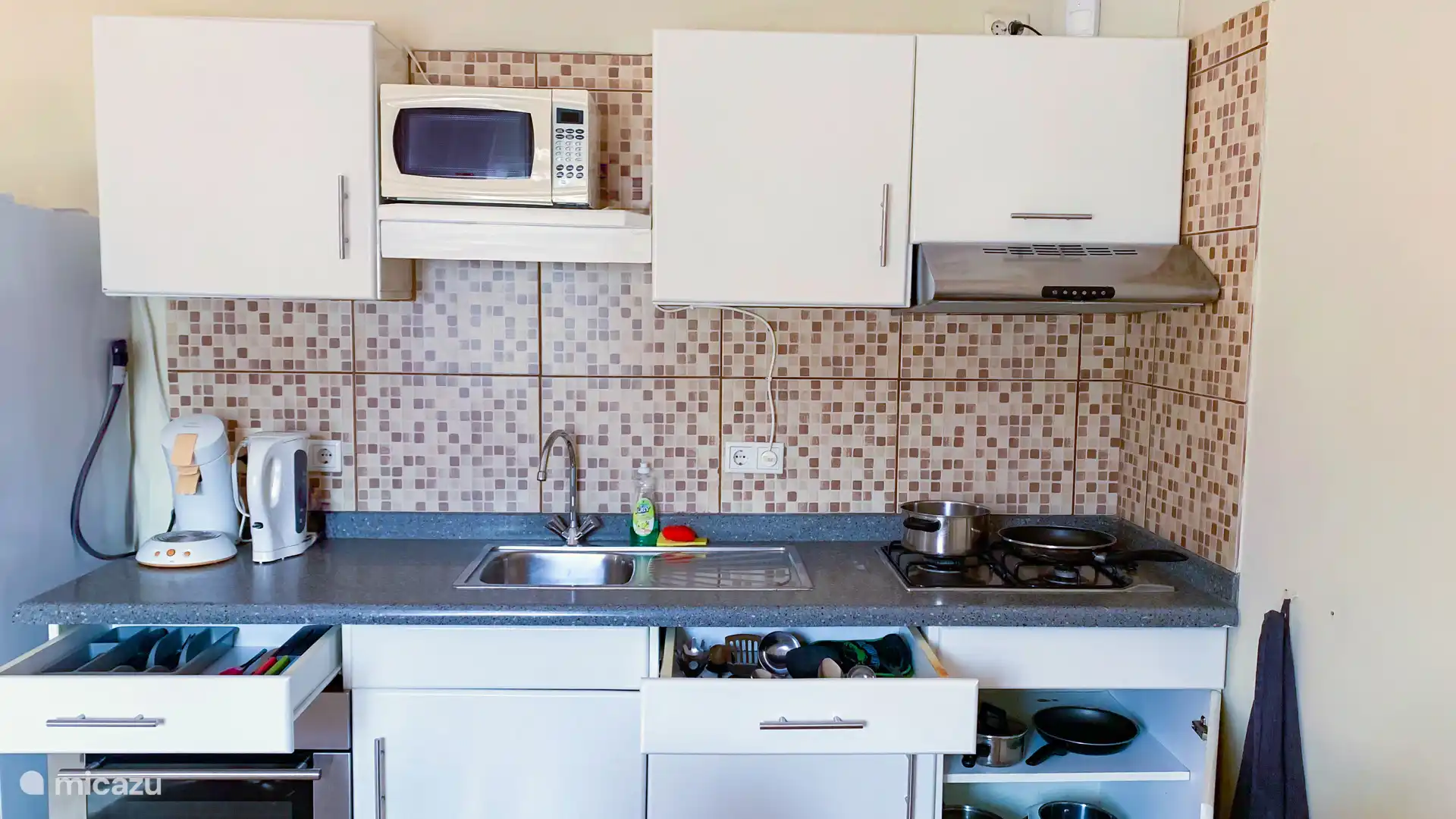 Fully equipped kitchen with stove, oven, microwave, coffee maker, kettle, refrigerator, plates, cutlery, pans, pots, etc.