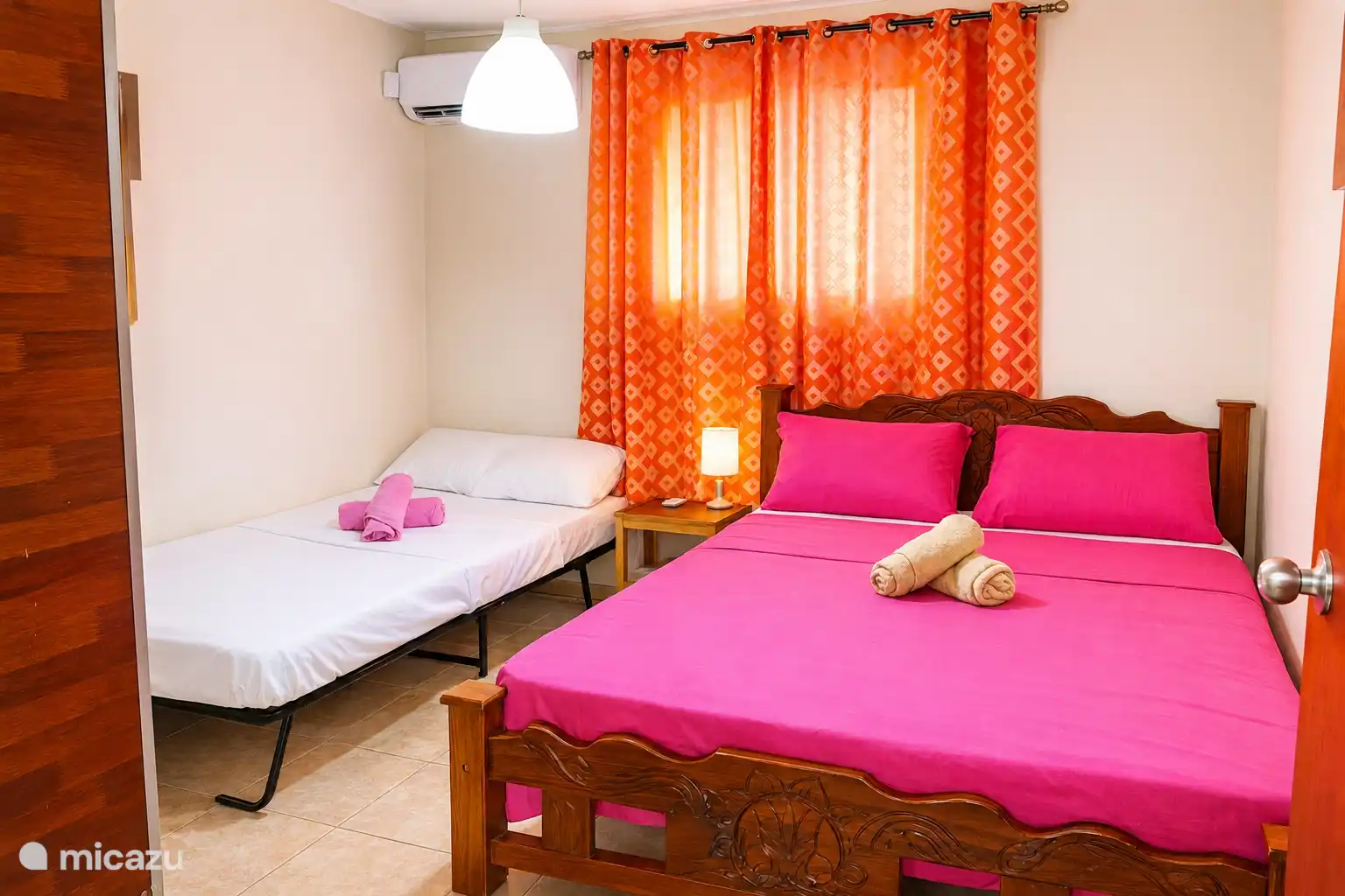 Air-conditioned bedroom with a double bed & a twin bed, wardrobe, mirror, and towels. 