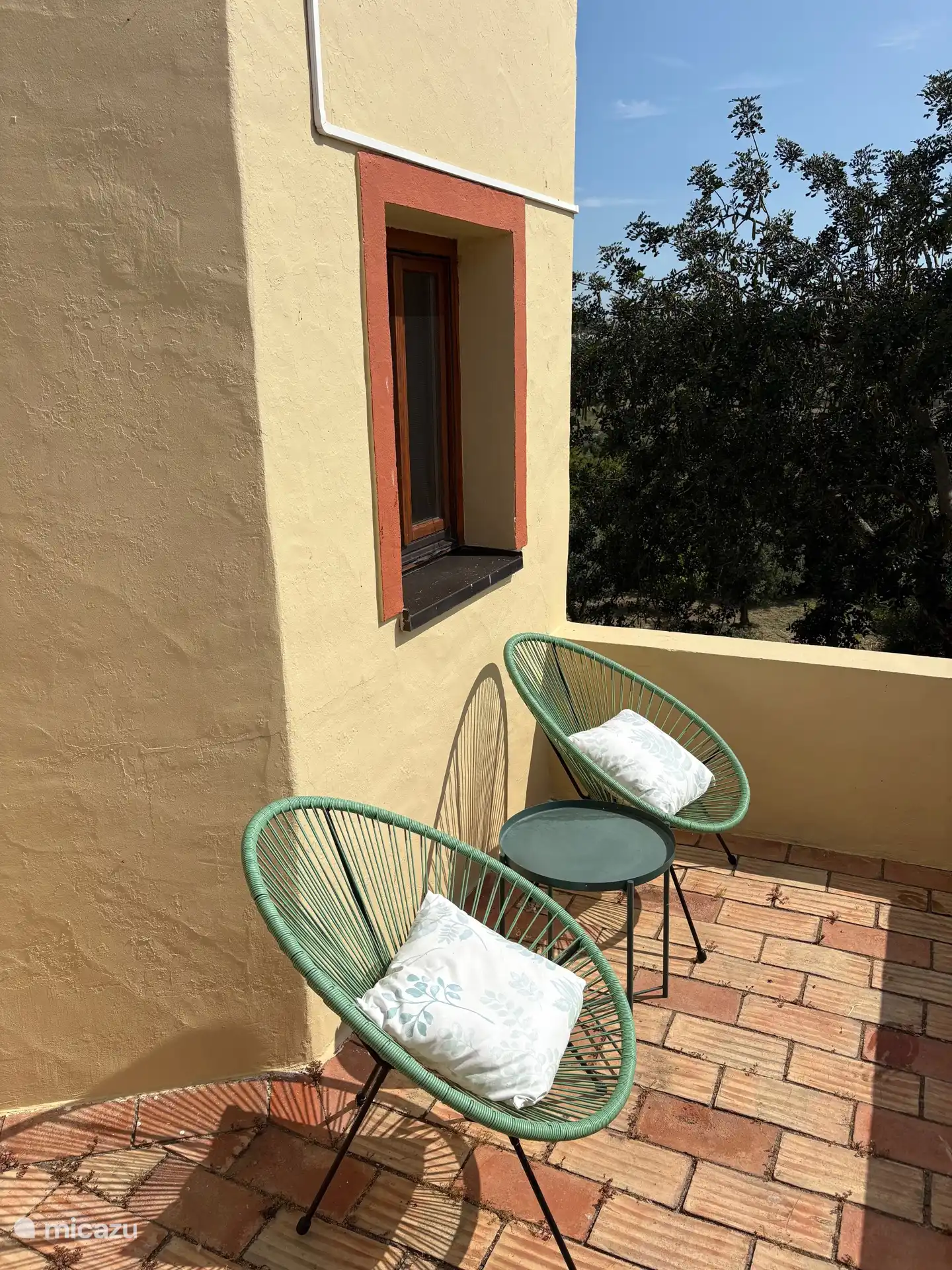 Balkonterrasse mit Stühlen und Tisch, ideal, um den Sonnenaufgang zu beobachten.