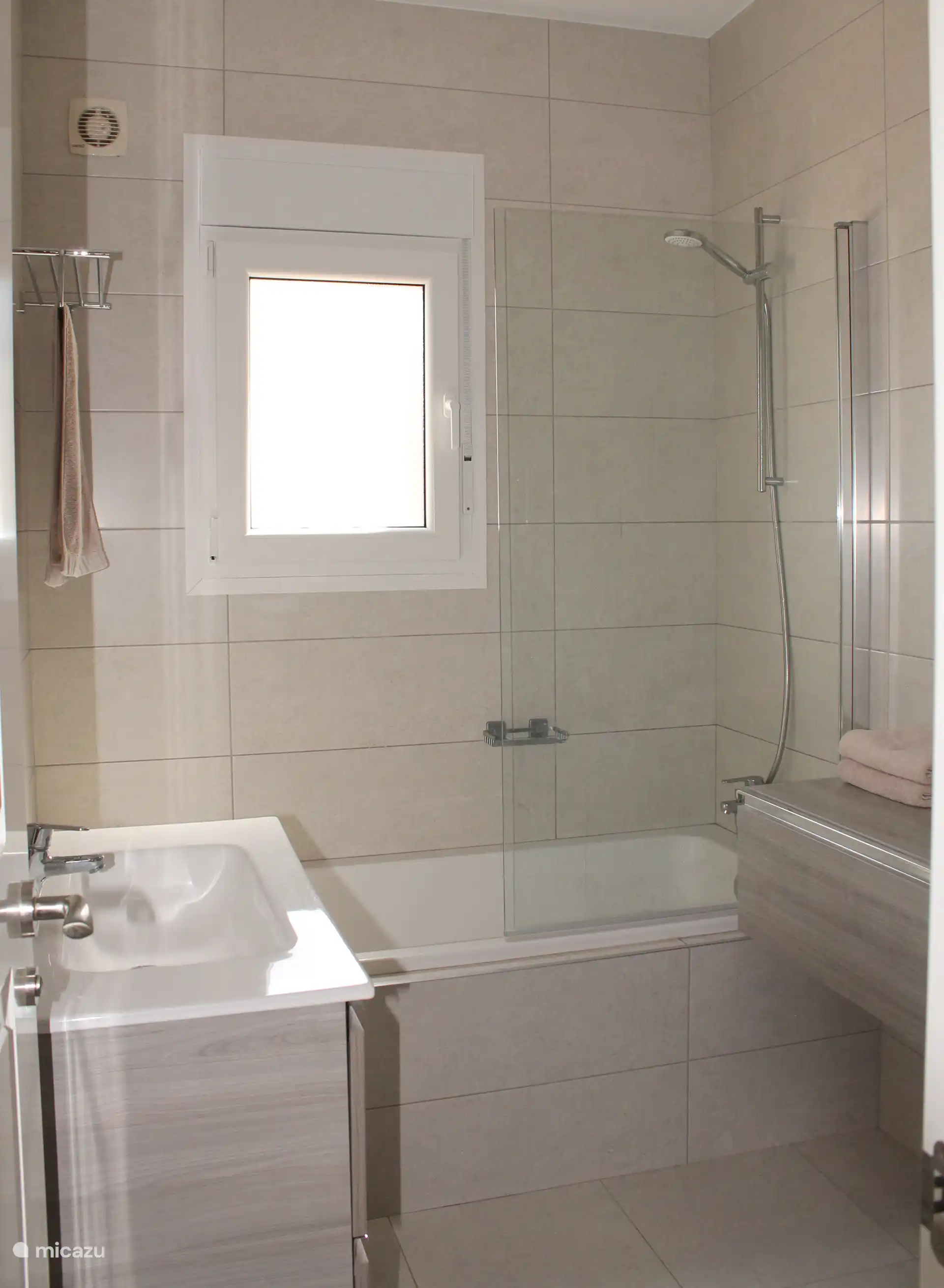 Badkamer met wastafel, bad en douche en toilet