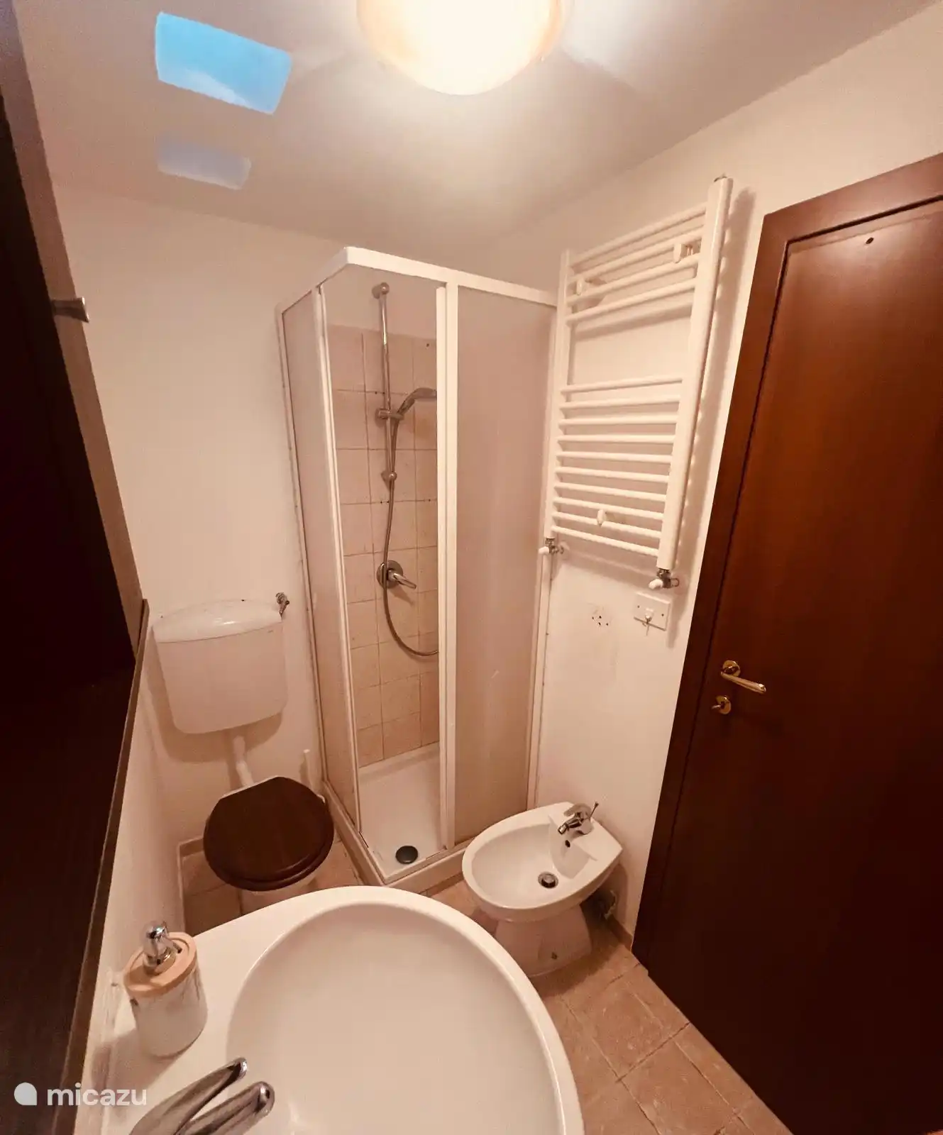 La salle de bain principale est idéalement située à côté de la cuisine-salle à manger ouverte. Douche compacte, toilettes, bidet et lavabo.