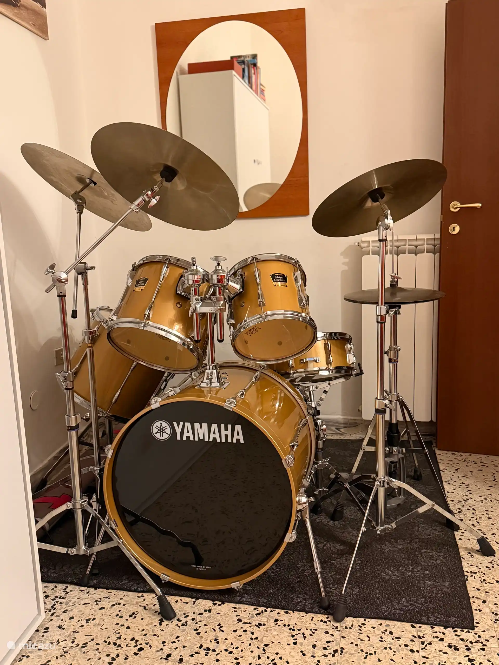 Wohnzimmer mit Wandsofa, Schlagzeug und Gitarre – ein gemütlicher kreativer Raum zum Entspannen oder Musizieren in der Nähe des Römischen Sees.