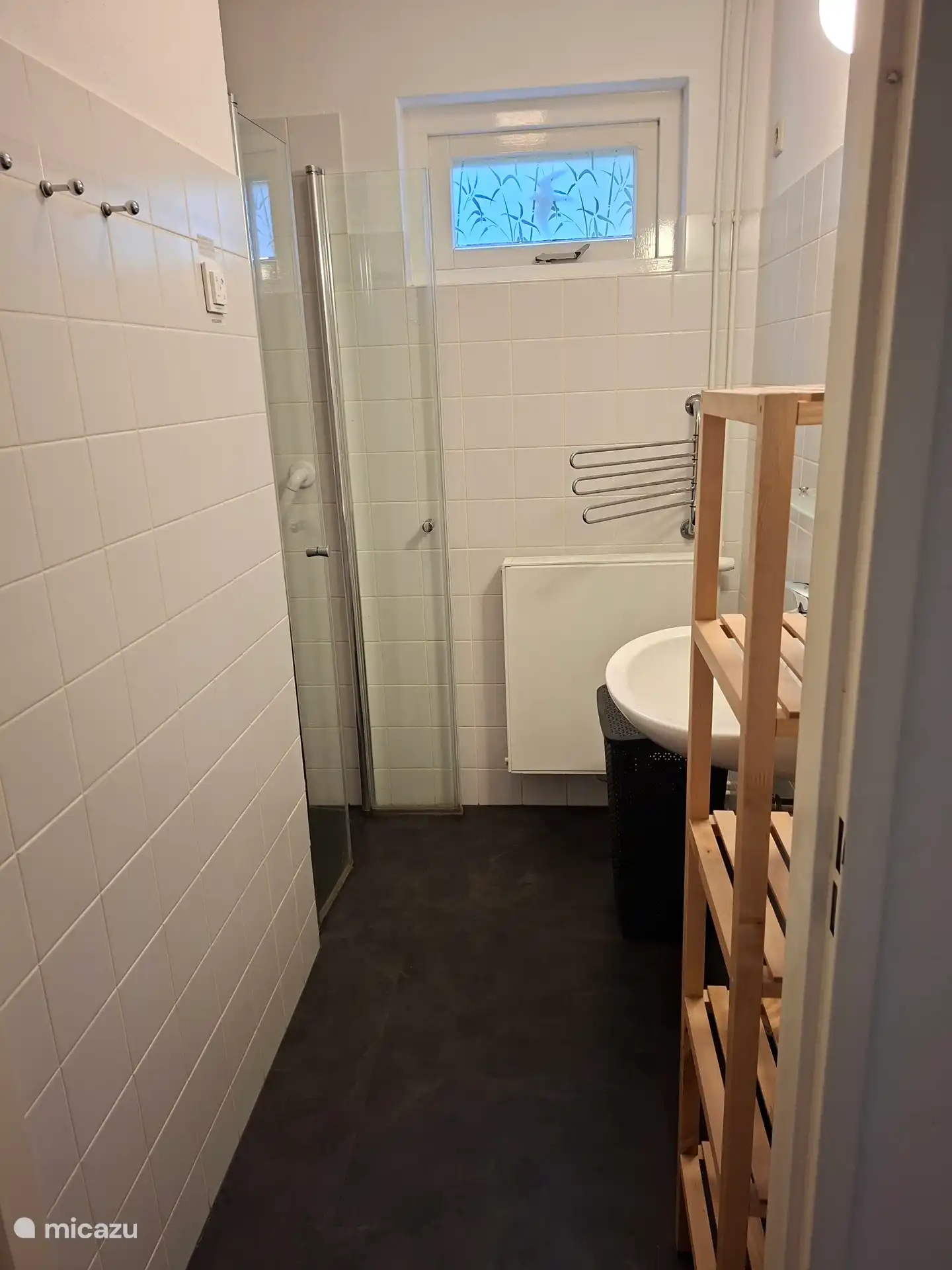 Das Badezimmer befindet sich im Erdgeschoss mit mechanischer Belüftung, Wäschekorb, Waschbecken und Haltegriff in der Dusche