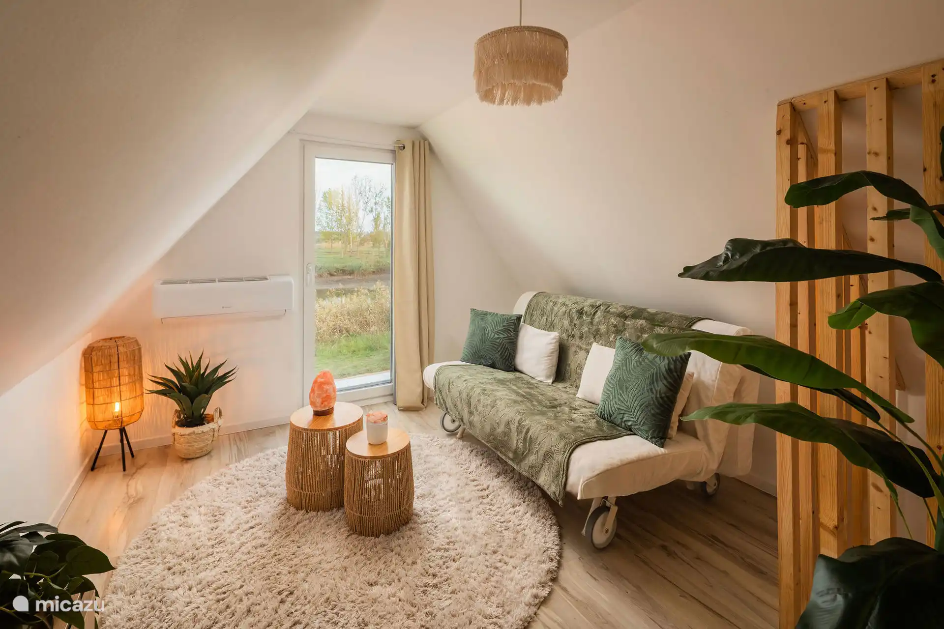 Deze zonnige hoek nodigt uit tot dagdromen, meditatie of een middagdutje. De bank verandert in een comfortabel tweepersoonsbed voor wie blijft slapen – of gewoon even niets wil.