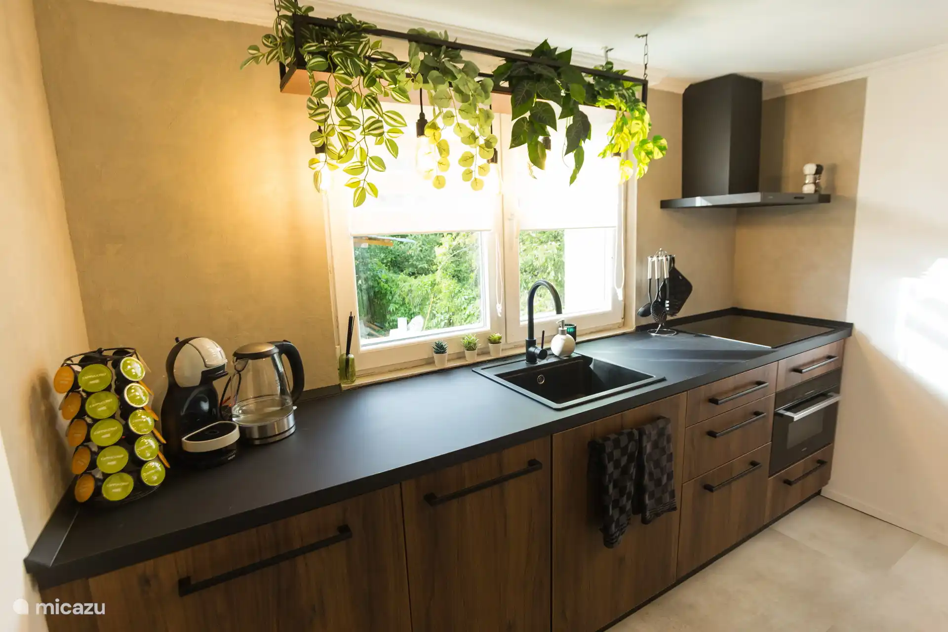 Une cuisine légère et moderne avec un look robuste, des tons de bois chauds et des détails verts. Tout est là pour un petit-déjeuner décontracté ou un dîner fait maison avec vue sur le jardin.