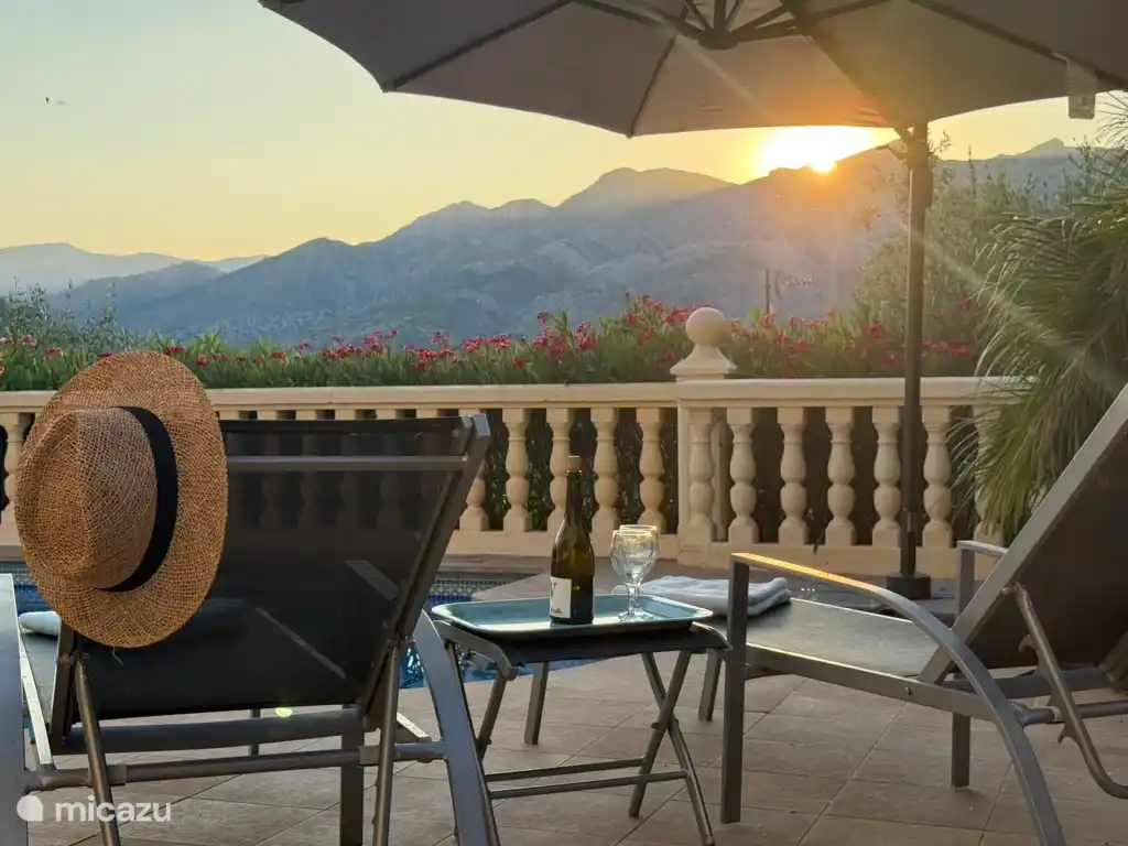 Schwimmbad und Sonnenliegen mit untergehender Sonne