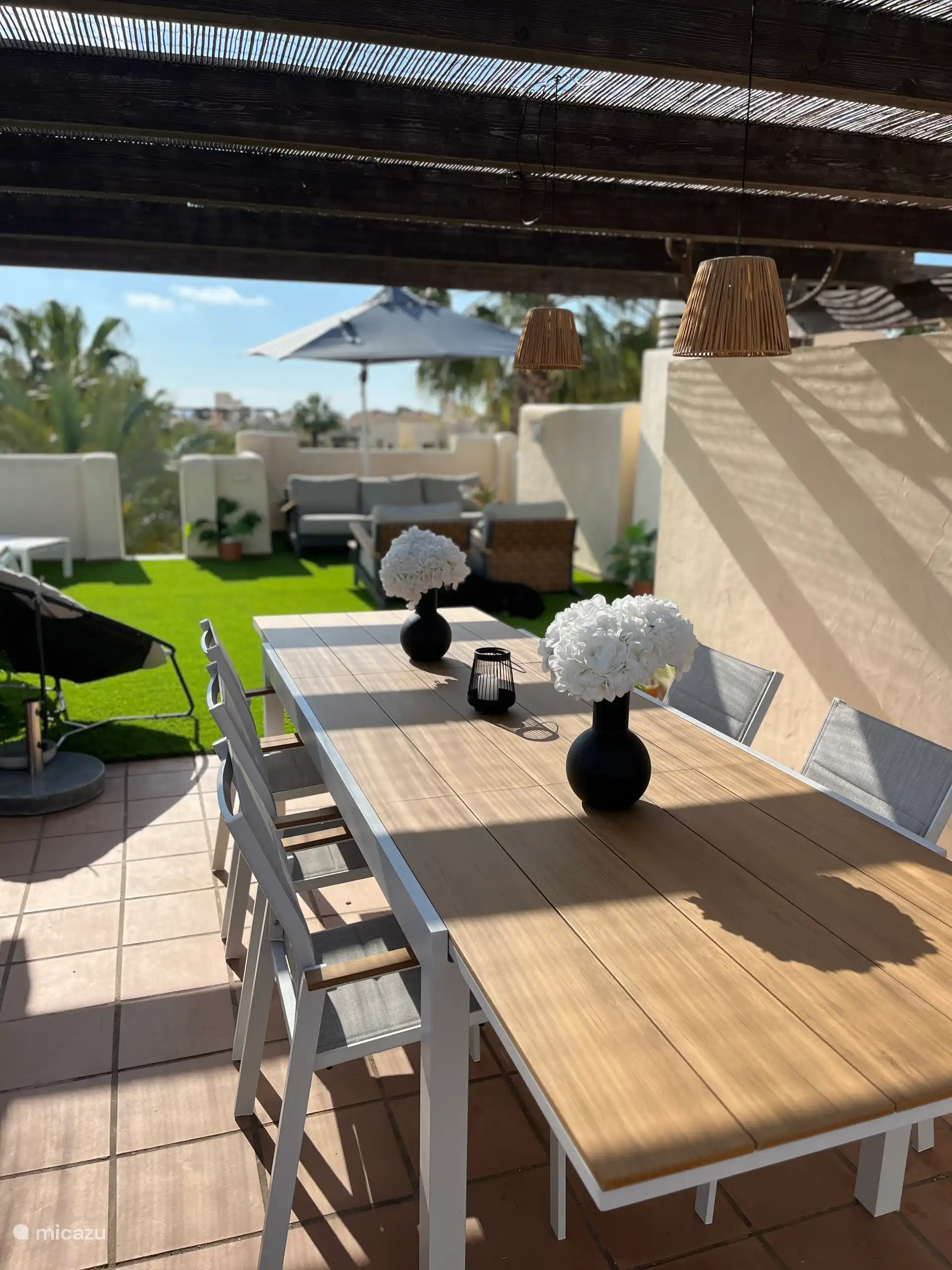 An diesem großen Esstisch auf der privaten Dachterrasse unter einem Reetdach können Sie eine Mahlzeit oder ein Getränk genießen. 