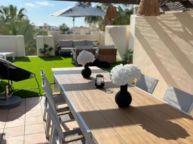 Location de Vacances Espagne, Costa Cálida, San Javier, penthouse - Penthouse Pentaguila  Sur cette grande table à manger sur le toit-terrasse privé sous un toit de chaume, vous pourrez prendre un repas ou une boisson.