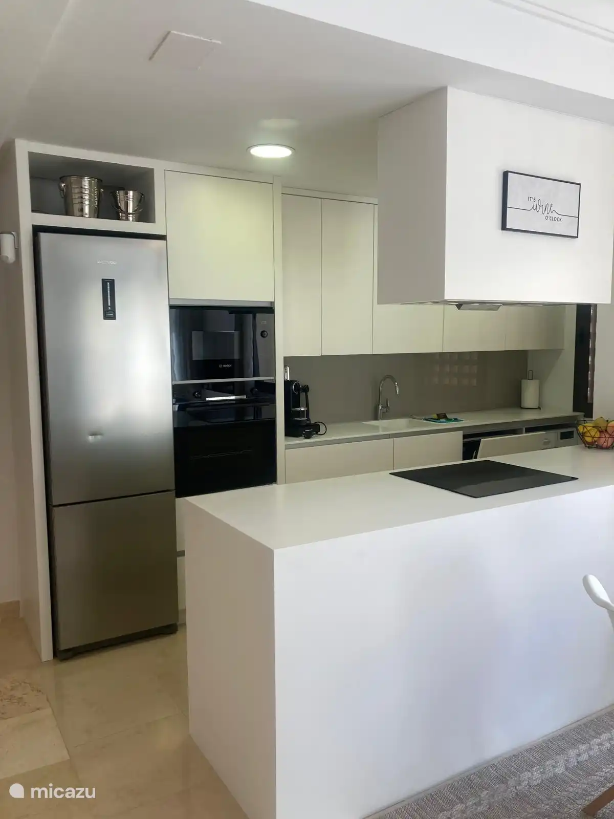 Die offene Küche ist mit einem Kühlschrank mit Gefrierfach, einer Mikrowelle, einem Heißluftofen, einem Induktionskochfeld, einem Geschirrspüler, einer Nespresso-Maschine und einer Waschmaschine ausgestattet. 