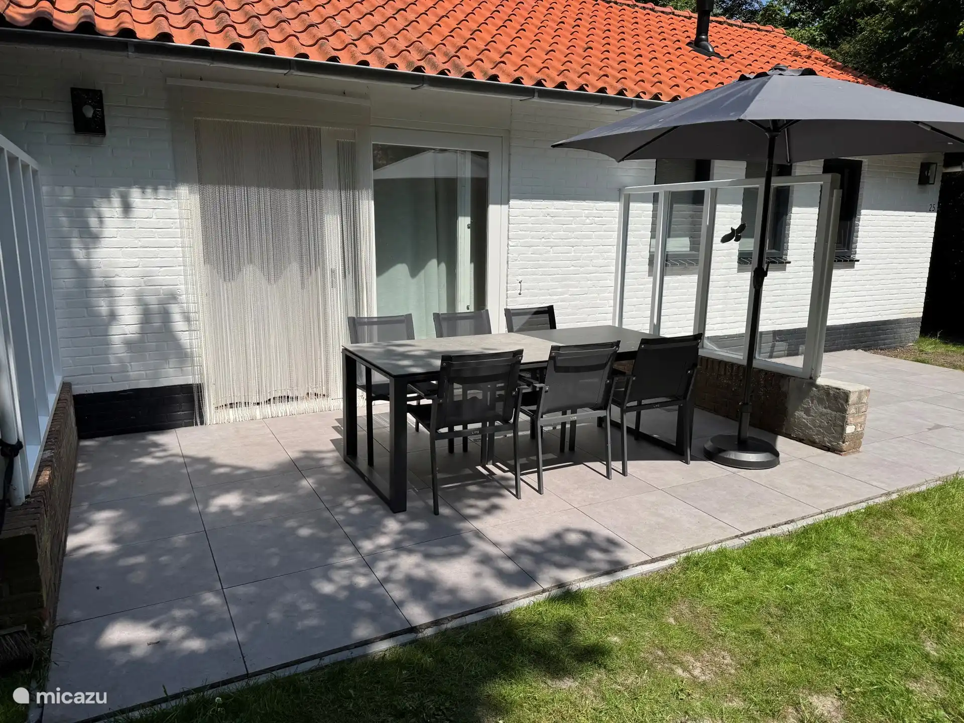 Ruime doorgang van tuindeur links naar terras