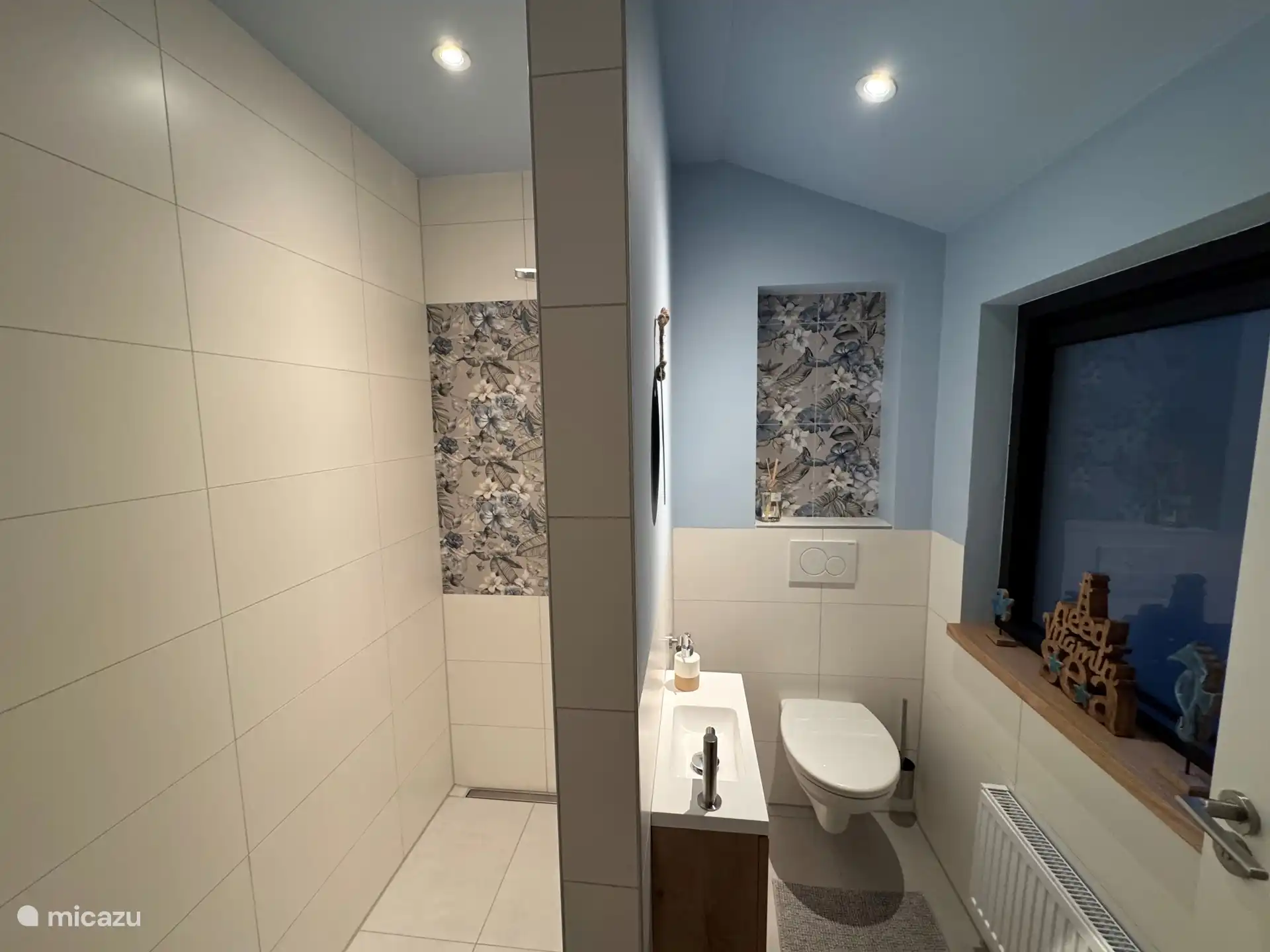 Links ruime douche rechts toilet, gescheiden door muur.