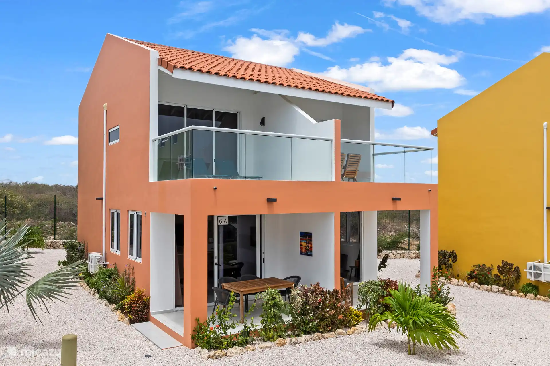 Die orangefarbene Fassade verleiht dem Haus ein warmes Aussehen, schön eingebettet in das umliegende Grün.