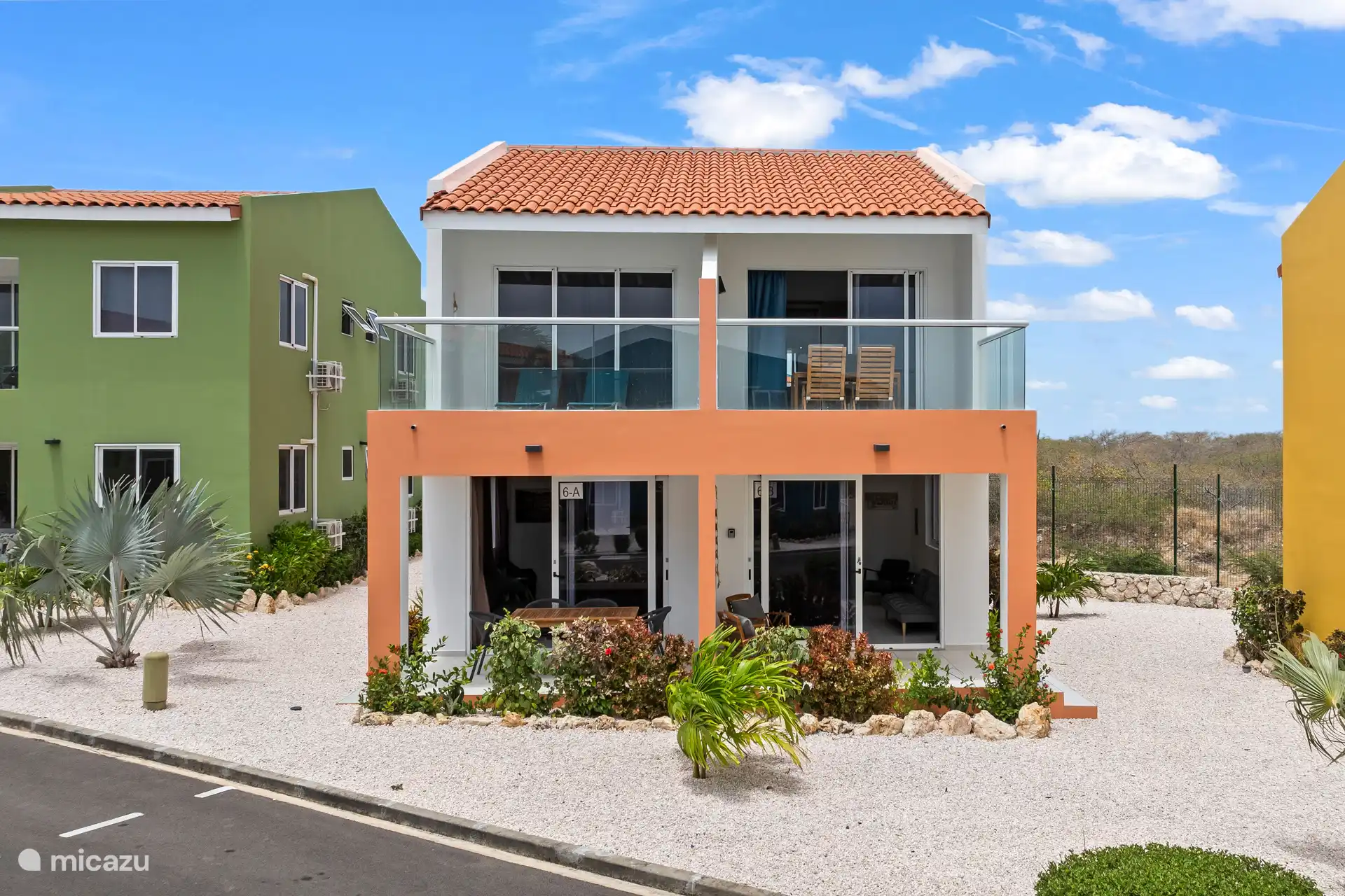 Die orangefarbene Fassade verleiht dem Haus ein warmes Aussehen, schön eingebettet in das umliegende Grün.