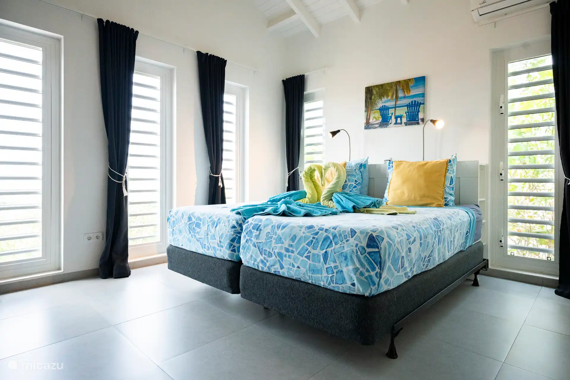 Ein helles und frisches Schlafzimmer mit bequemen Betten, Klimaanlage, vielen Fenstern und tropischem Grün rundherum. Beinhaltet einen geräumigen Wäscheschrank und eine Kommode – ideal für längere Aufenthalte und viel Bequemlichkeit.