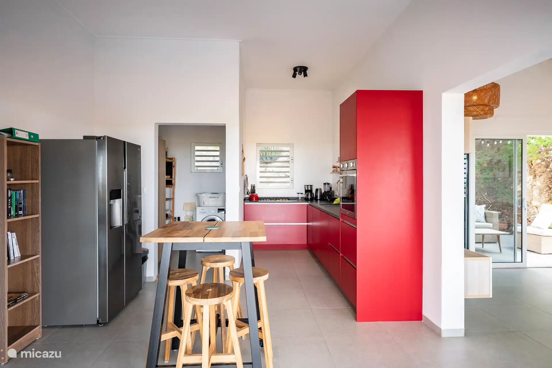 Eine moderne Küche mit großzügigem amerikanischen Kühlschrank und einem praktischen Hauswirtschaftsraum mit Waschmaschine direkt daneben. Ideal für einen komfortablen und unbeschwerten Aufenthalt auf Curaçao.