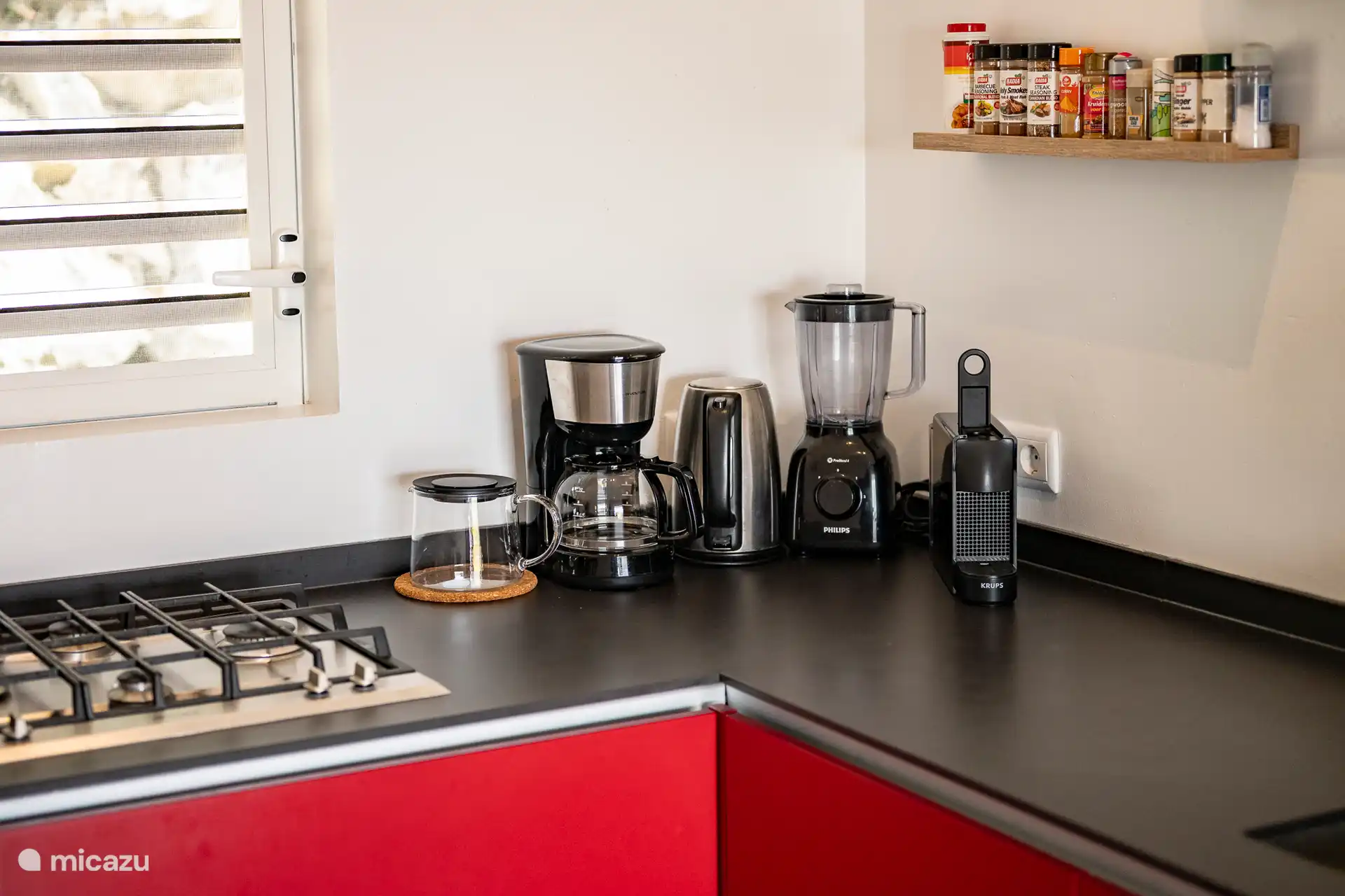 Moderne Küche mit allen Annehmlichkeiten: Gasherd, Kaffeemaschine, Mixer, Wasserkocher und geräumige Arbeitsplatten. Perfekt ausgestattet, um selbst zu kochen und zu Hause eine komfortable Mahlzeit zu genießen.