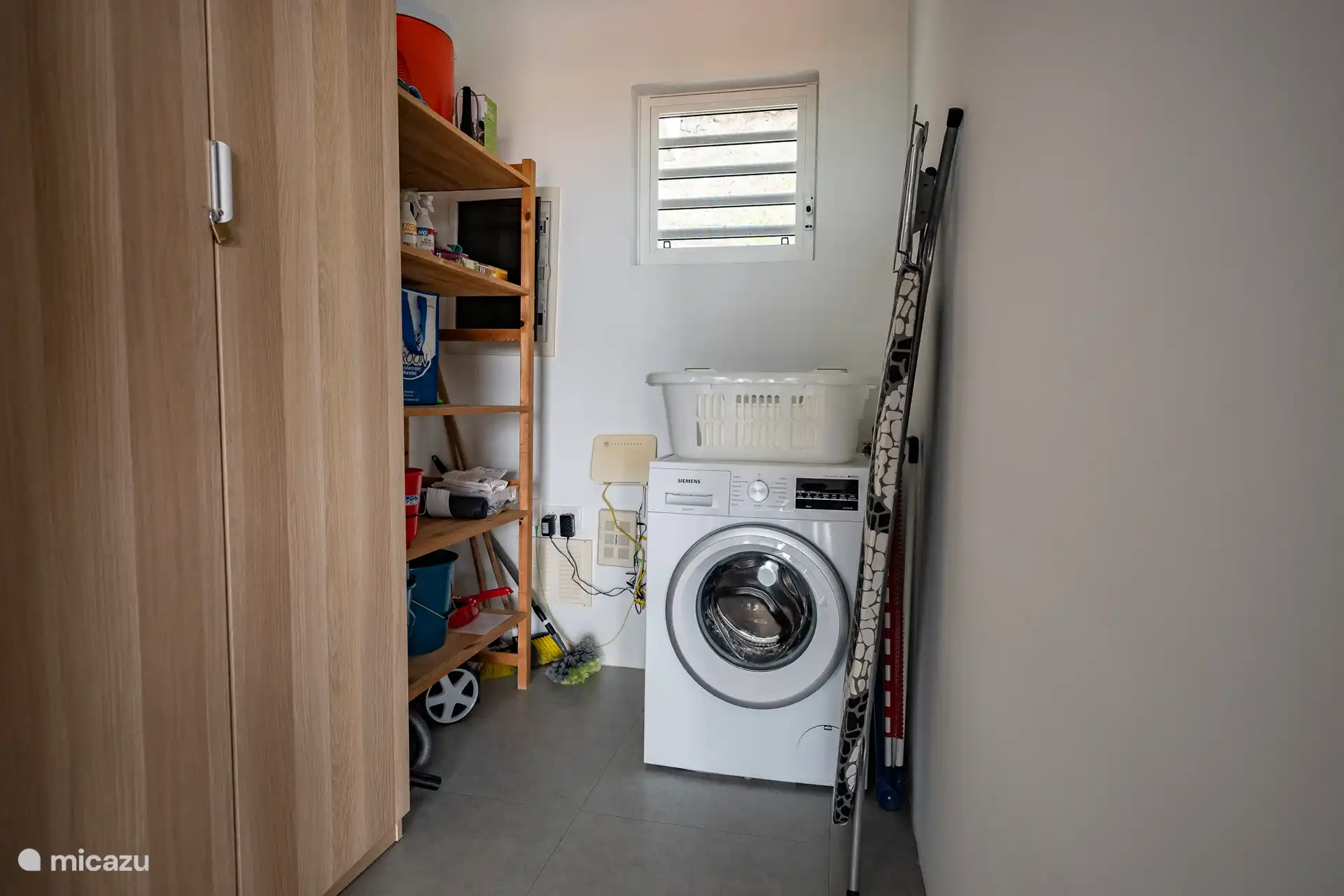 Praktischer Hauswirtschaftsraum mit Waschmaschine, Bügelbrett, Reinigungsutensilien und zusätzlichem Stauraum. Praktisch für längere Aufenthalte und um alles frisch und organisiert zu halten.