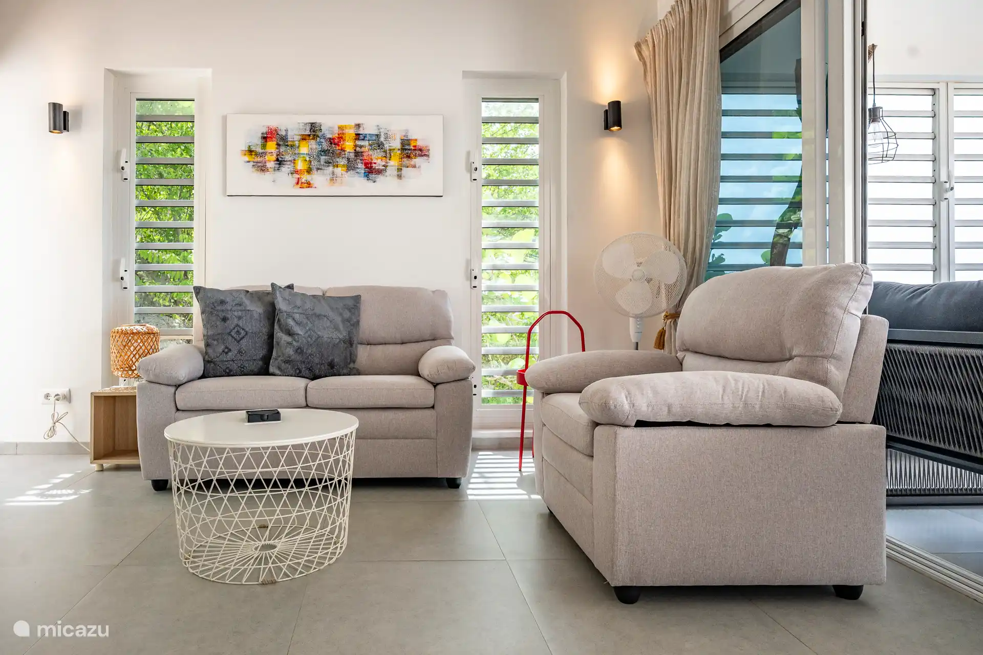 Ein fröhlicher, heller Sitzbereich mit weichen Sesseln, farbenfroher Kunst und tropischem Grün um dich herum. Der perfekte Ort, um sich hinzusetzen und zu entspannen.