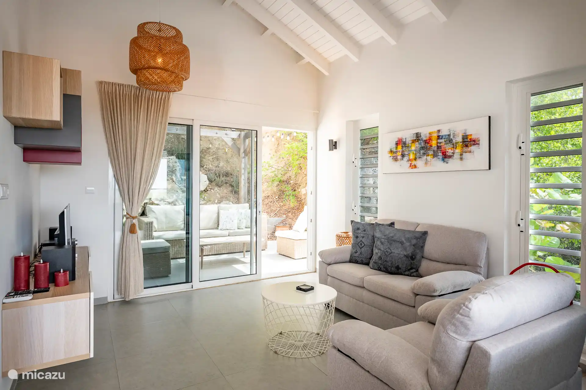 Ein helles und attraktives Wohnzimmer mit gemütlichem Sitzbereich, wunderschöner Blick auf die hintere Terrasse, ein Flachbildfernseher und ein Kühlventilator. Der ideale Ort zum Entspannen 