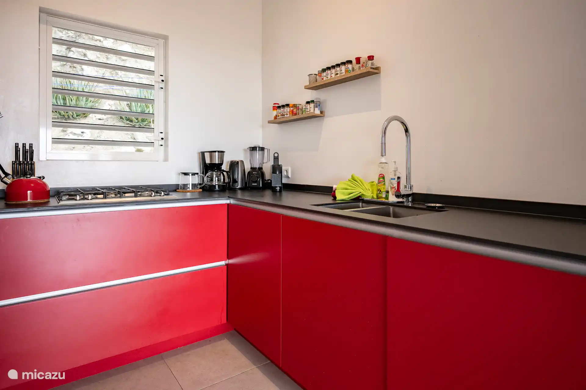 Eine moderne, voll ausgestattete Küche mit auffälligen roten Schränken, luxuriösen Geräten und allem, was Sie brauchen, um während Ihres Aufenthalts köstliche Mahlzeiten zuzubereiten. Praktisch und stilvoll