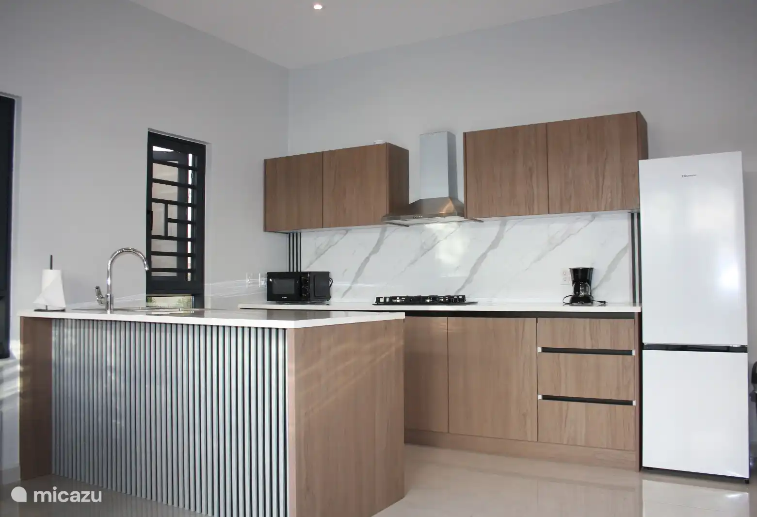 Modern and functional kitchen with double sink, gas hob with electric ignition, microwave and fridge-freezer.