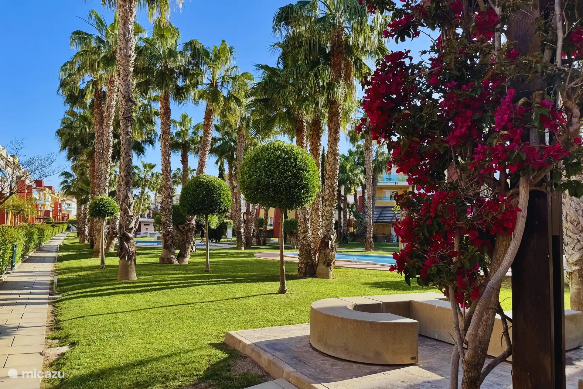 Jardin magnifiquement entretenu avec des fleurs colorées et des coins salon ombragés.