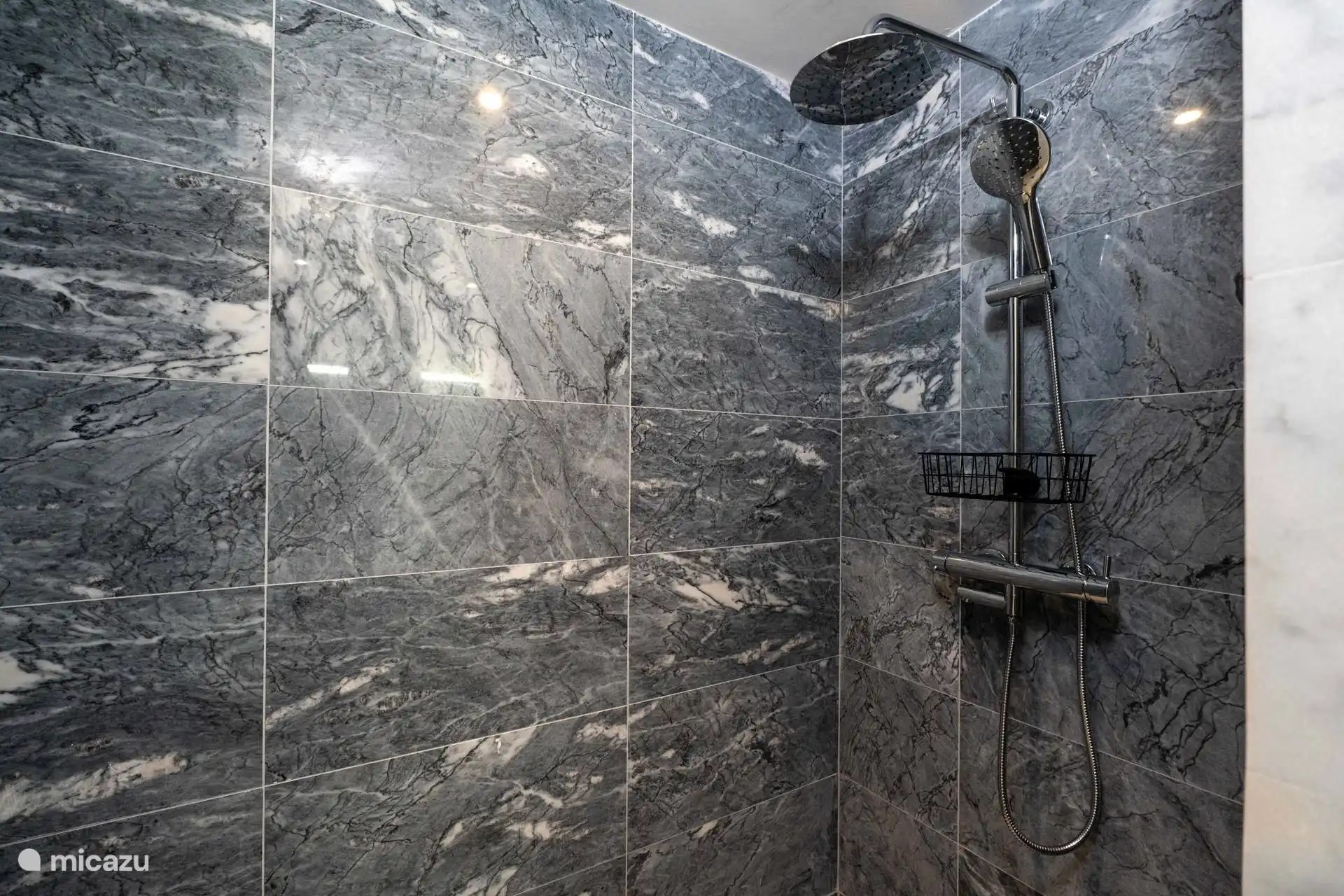 Douche à l’italienne très spacieuse avec douche à effet pluie et entièrement finie en marbre.