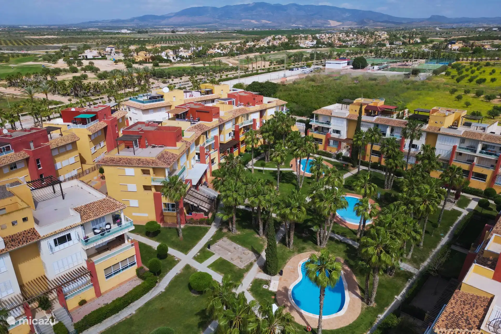 Vue aérienne du jardin magnifiquement aménagé avec quatre piscines, à seulement une minute à pied de l’appartement.