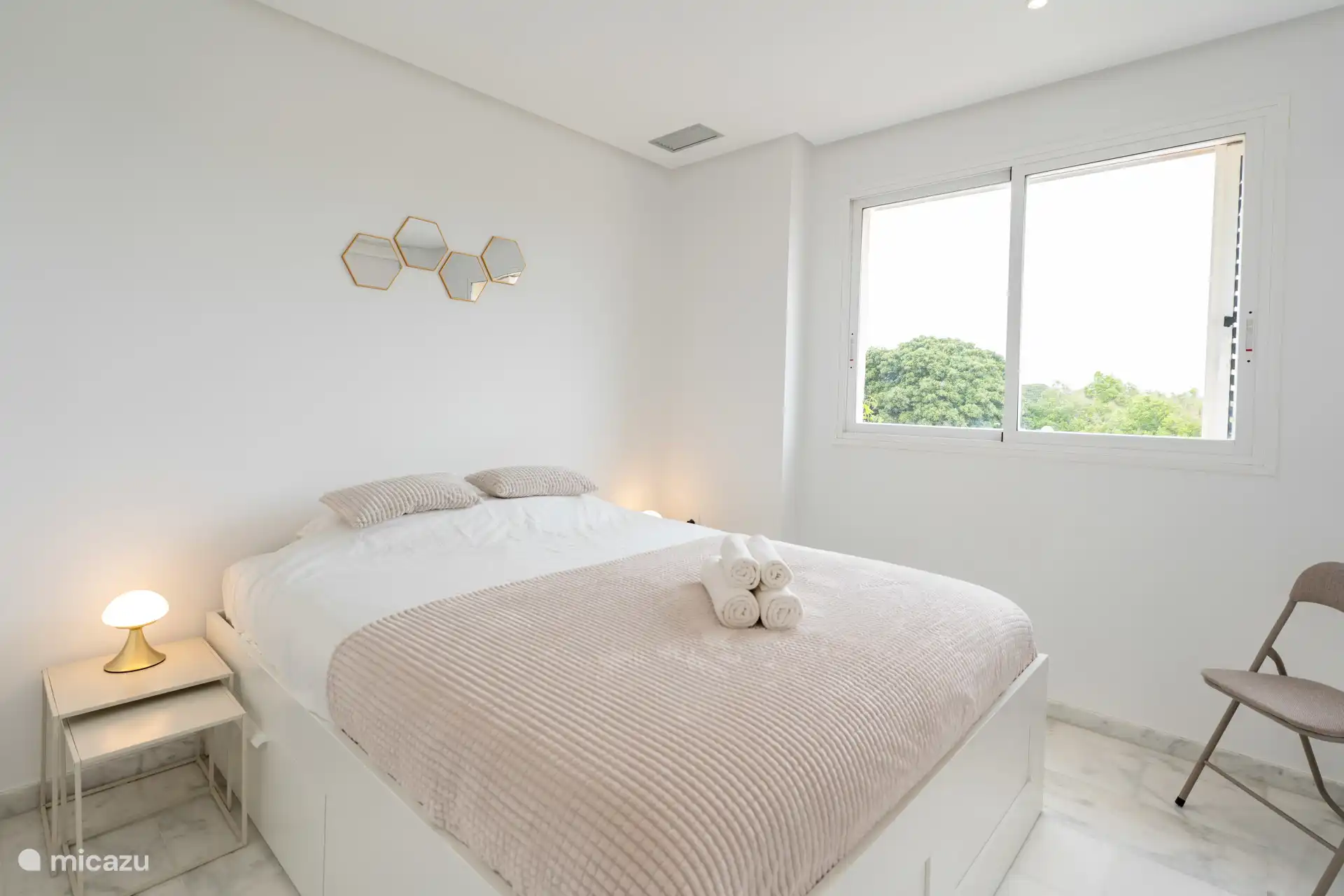 Chambre double avec lit queen (160 × 200), armoire intégrée et une grande fenêtre qui laisse entrer beaucoup de lumière naturelle.