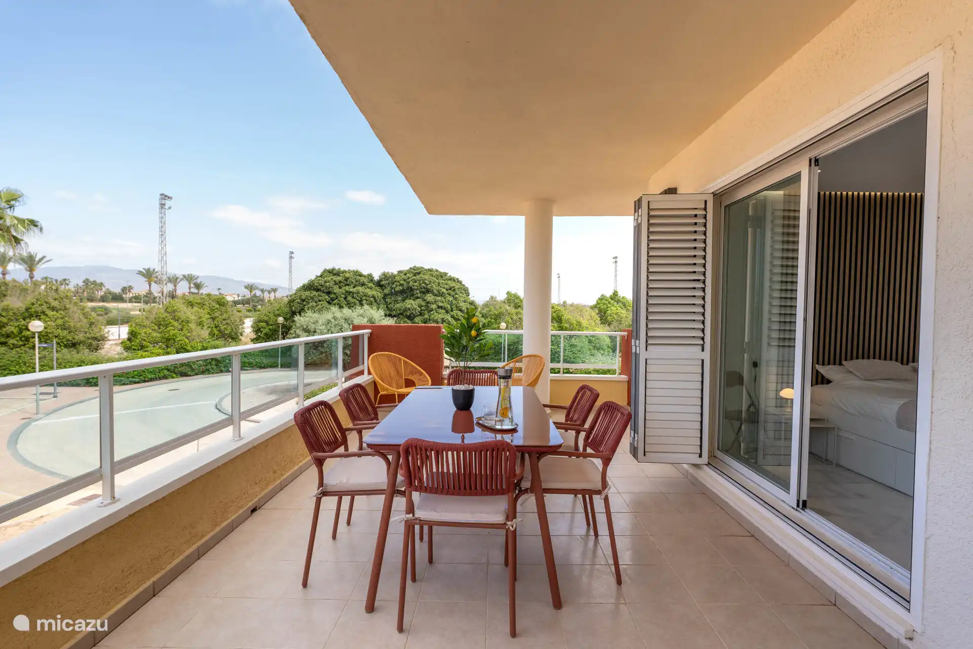 Terrasse spacieuse avec coin repas et chaises confortables, entourée de verdure et avec une vue imprenable sur les palmiers.